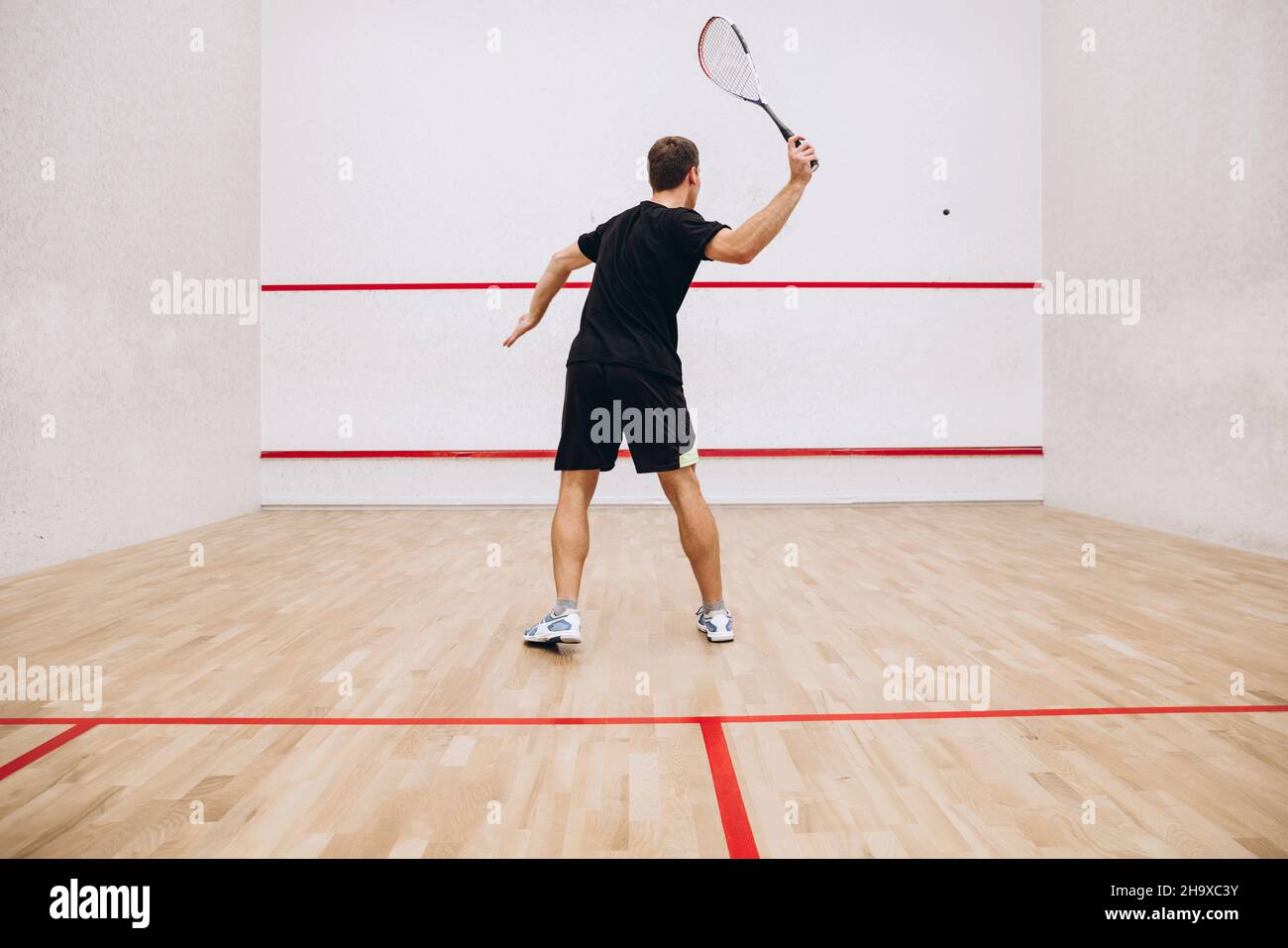 Back view of man playing squash game alone in sport studio Stock Photo