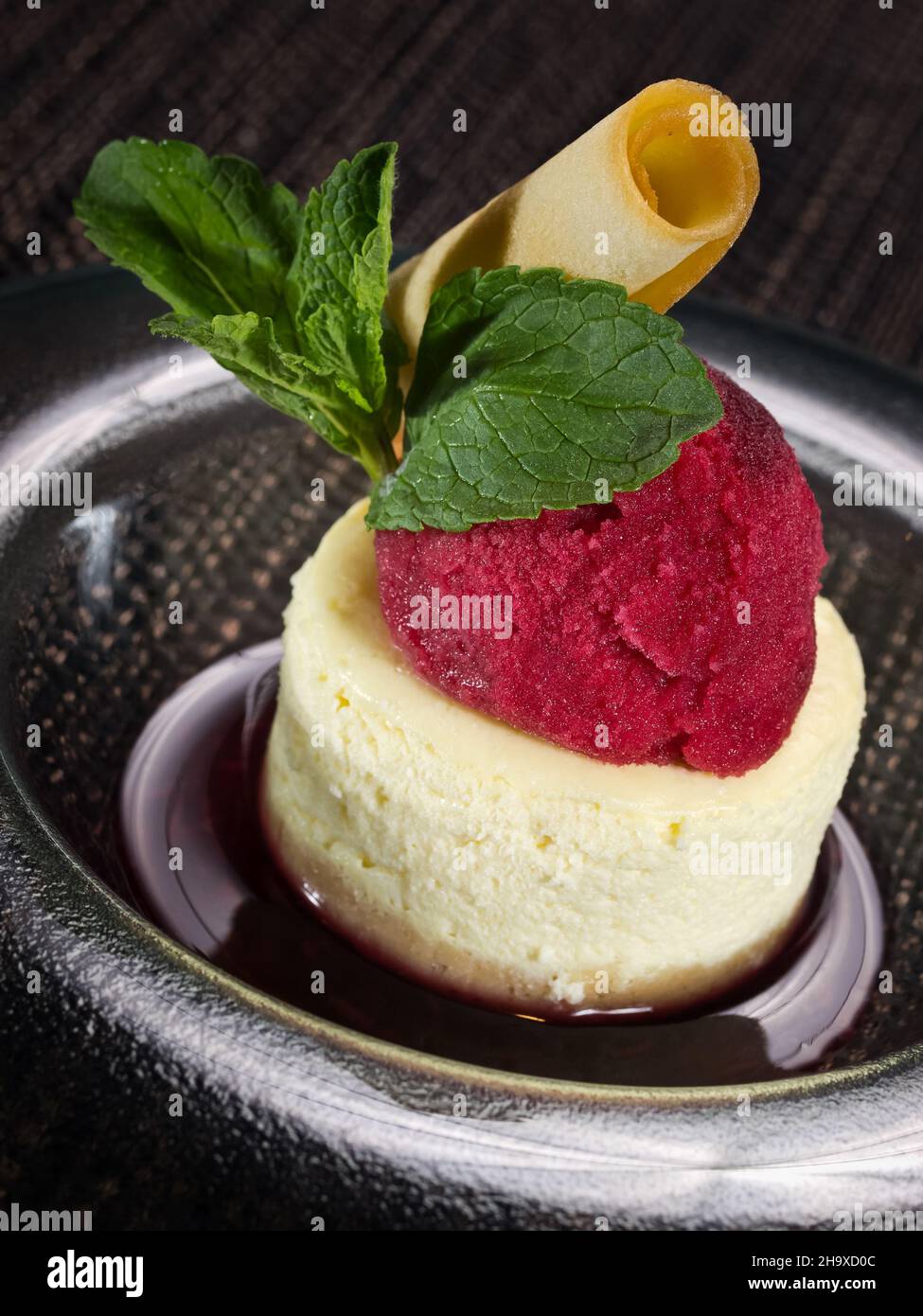 sweet dessert panna cotta in cherry sauce and scoop of cherry sorbet, vertical photo on dark background Stock Photo
