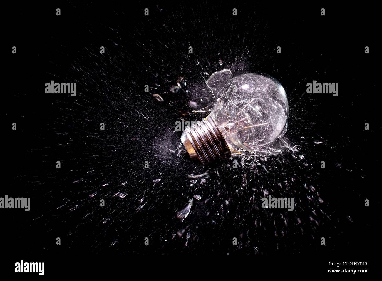 moment of impact explosion of a traditional light bulb on a black background. Stock Photo