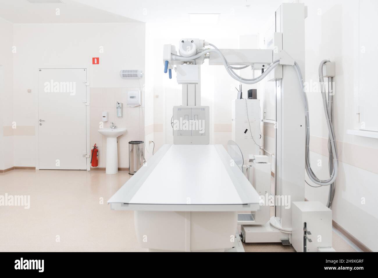 X-ray department in modern hospital. Radiology room with scan machine with empty bed. Technician adjusting an x-ray machine. Scanning chest, heart Stock Photo