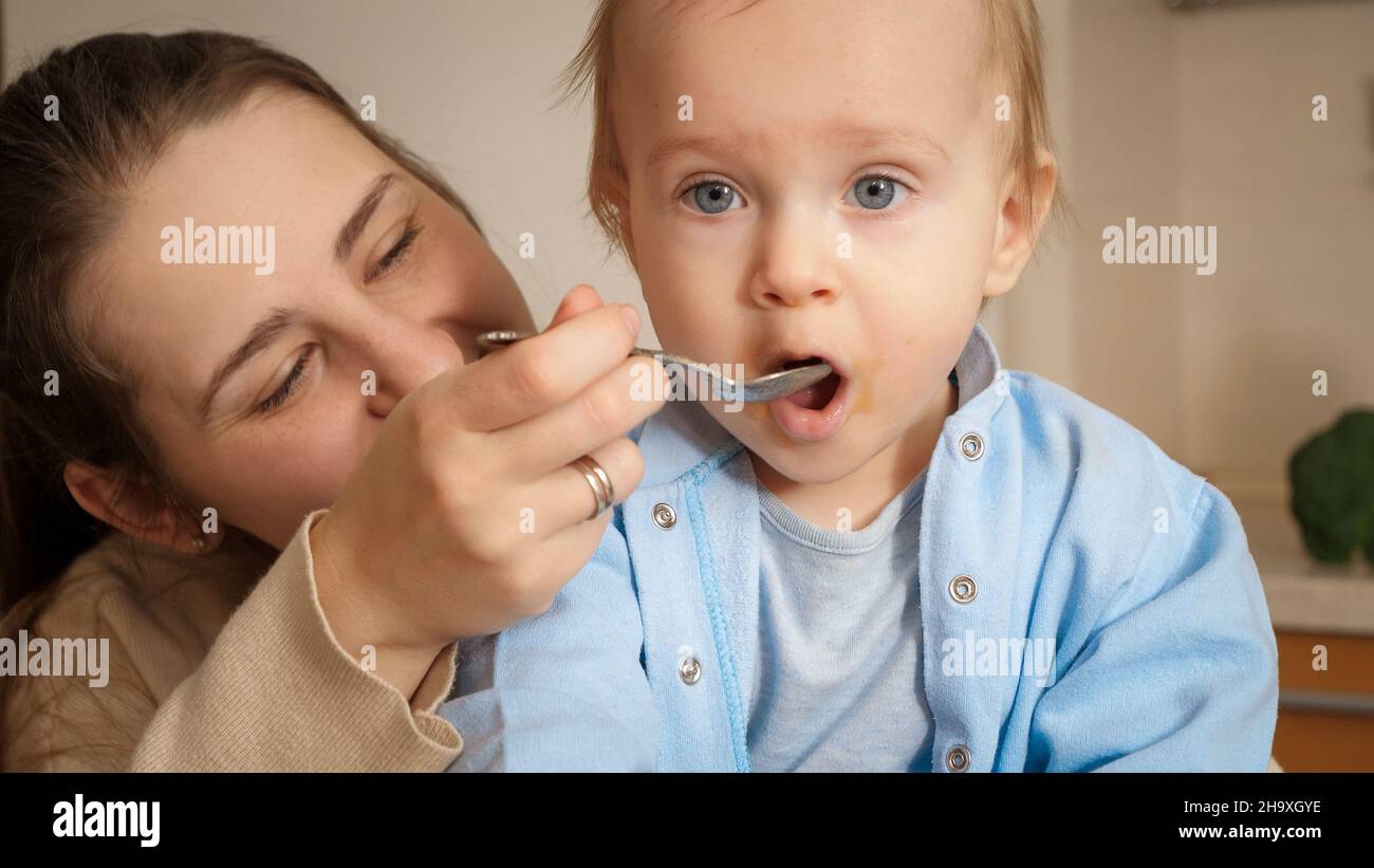 Portrait of little baby boy opening mouth while eating porridge with