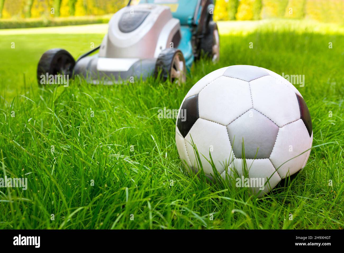 A football ball and a lawn mower in the green grass, a closeup Stock