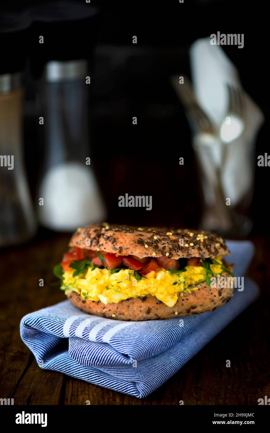 A corn bagel with egg and cress with mayonnaise, rocket and tomato