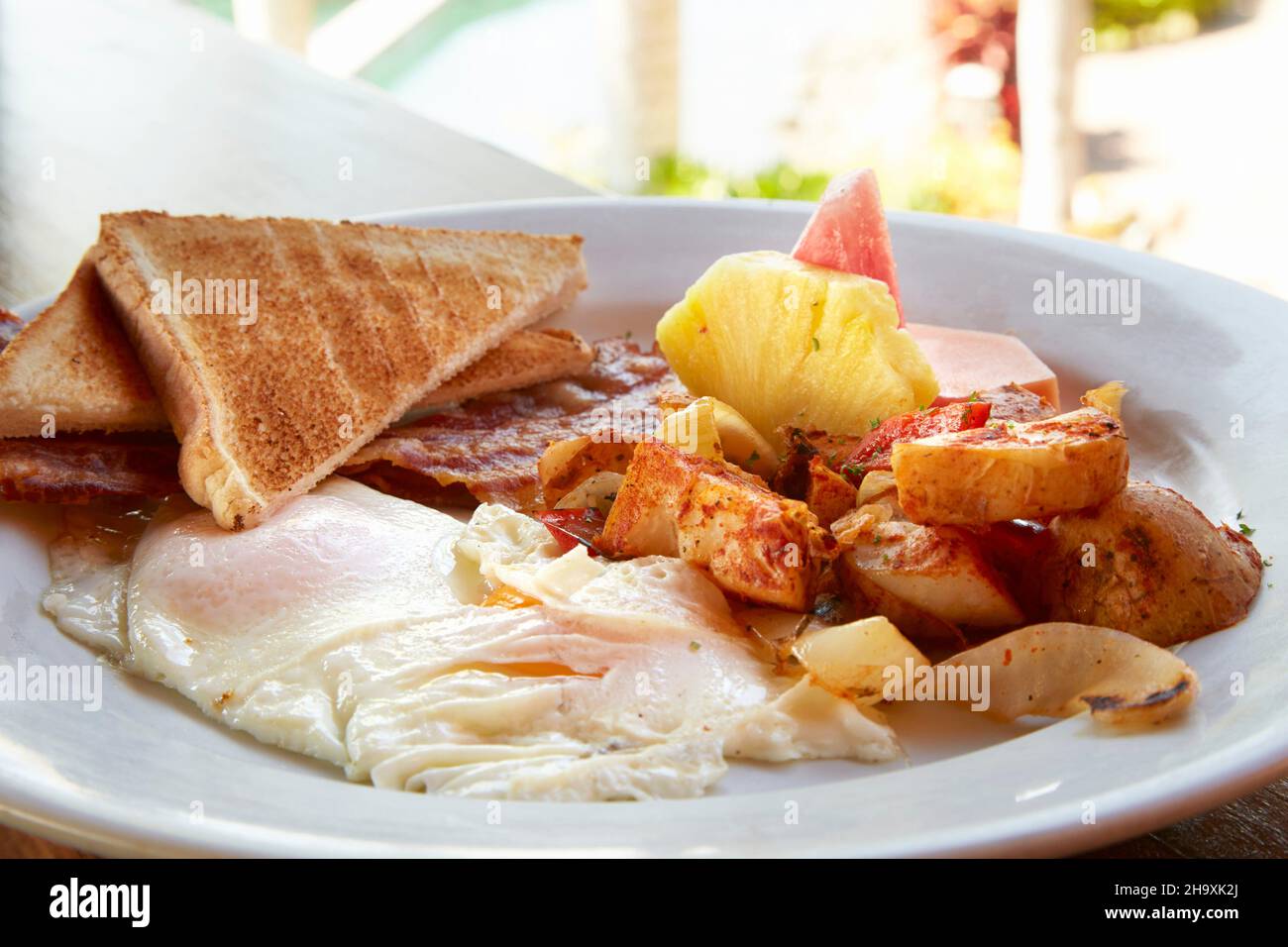Breakfast of fried eggs, bacon, potatoes, toast and pineapple (Costa