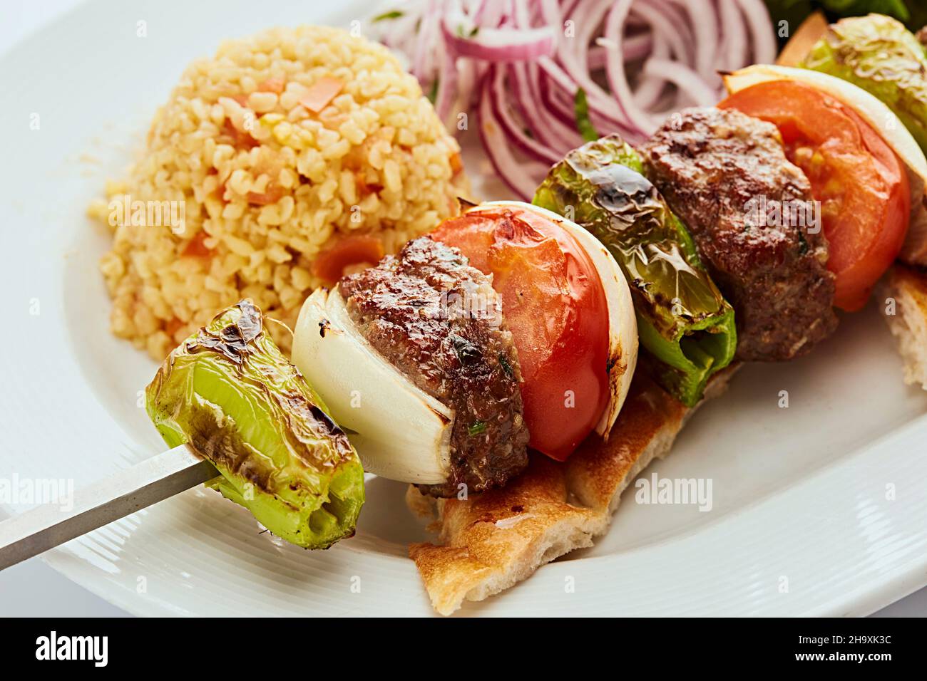 Minced beef skewer with onion, green pepper and tomato served with rice