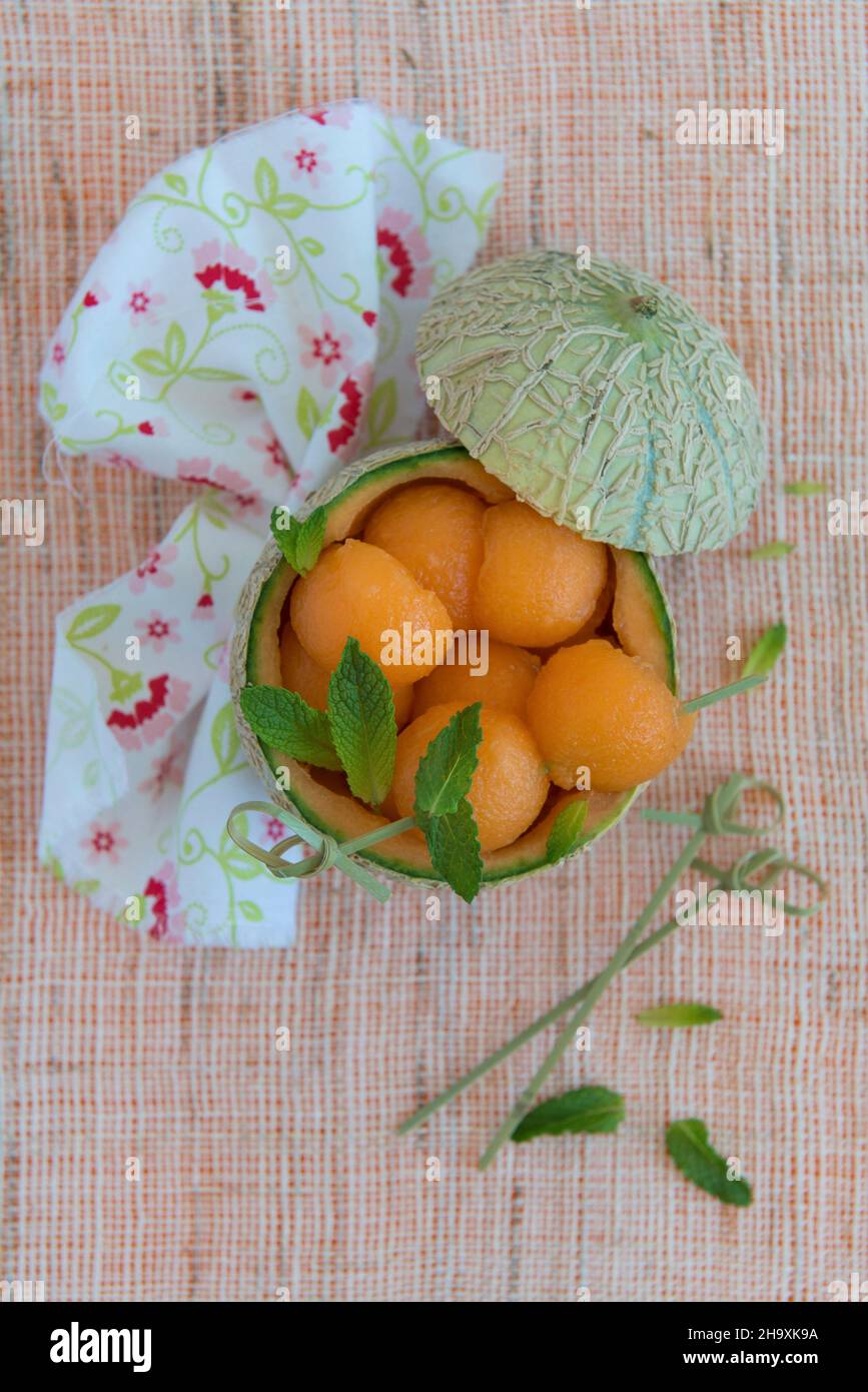 Melon balls inside scooped out melon Stock Photo