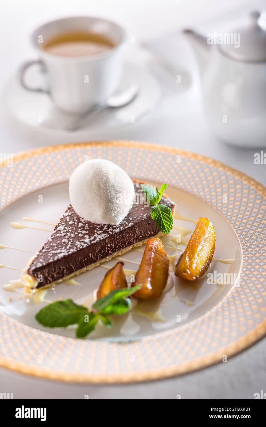 Chocolate tart with creme anglaise, pears and a scoop of milk ice cream on a festive plate Stock Photo