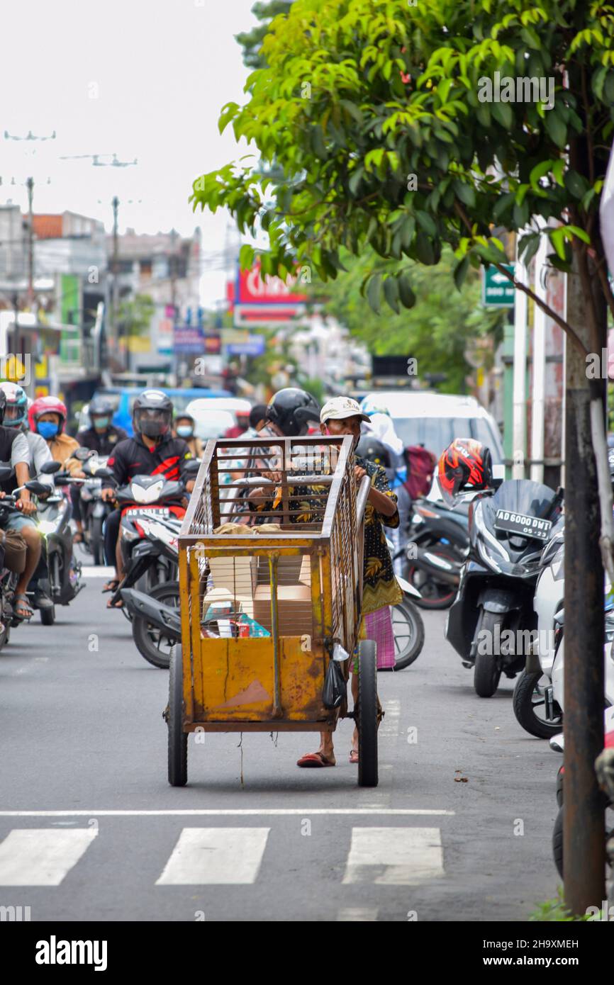 A hardworker scavenger pulling his cart in a cloudy morning after rain, on asphalt road. Solo - Indonesia. December 9, 2021 Stock Photo