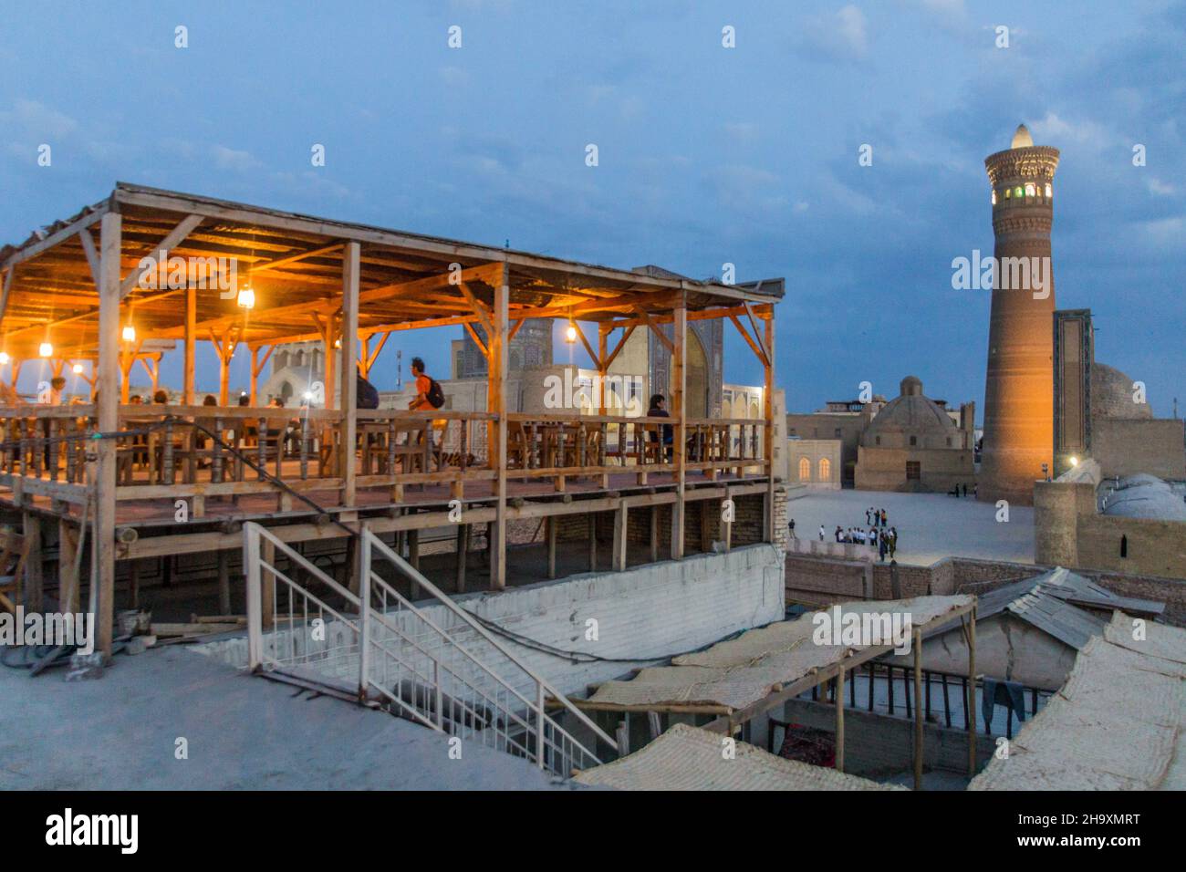 BUKHARA, UZBEKISTAN - APRIL 30, 2018: Evening view of Mir-i-Arab Madrasa, Kalan minaret and mosque and a cafe terrace in Bukhara, Uzbekistan Stock Photo