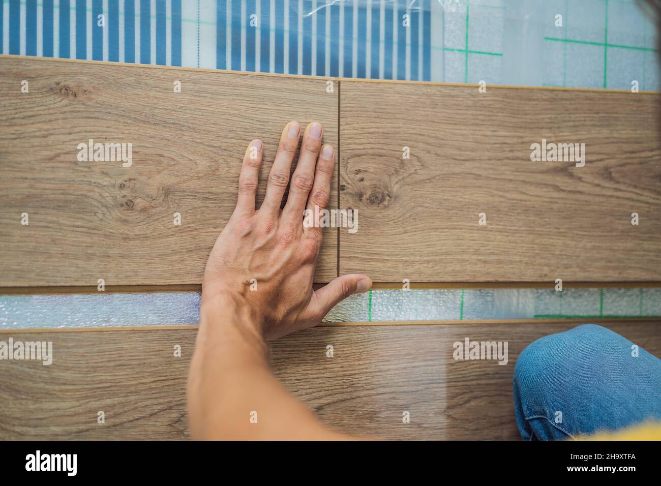 Man installing new wooden laminate flooring on a warm film floor