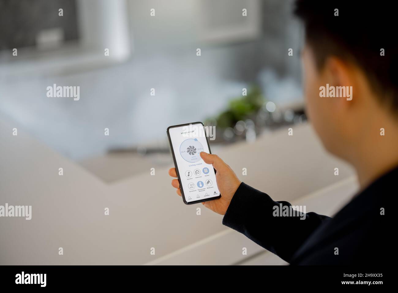 Man using app of smart home on smartphone Stock Photo
