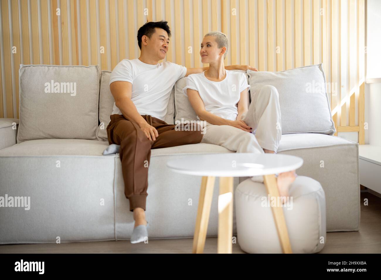 Multiracial couple sit and rest on sofa at home Stock Photo - Alamy