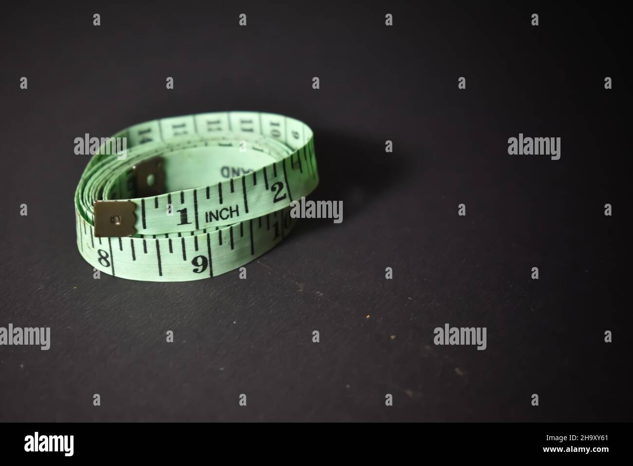 https://c8.alamy.com/comp/2H9XY61/a-selective-focus-picture-of-measuring-tape-with-inches-marked-on-it-against-a-black-background-2H9XY61.jpg