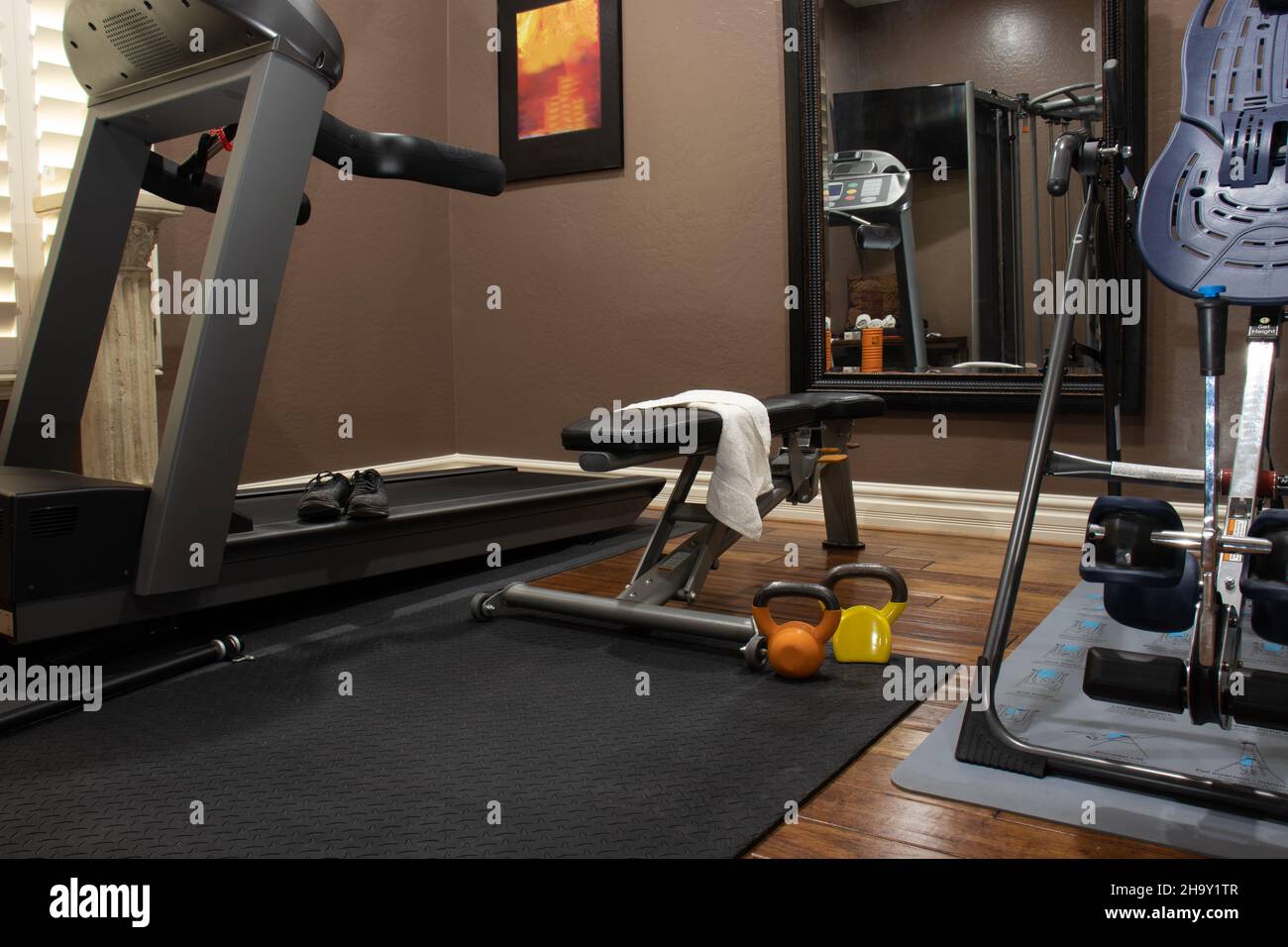 Home gym in spare bedroom with a treadmill, bench, and weights Stock Photo
