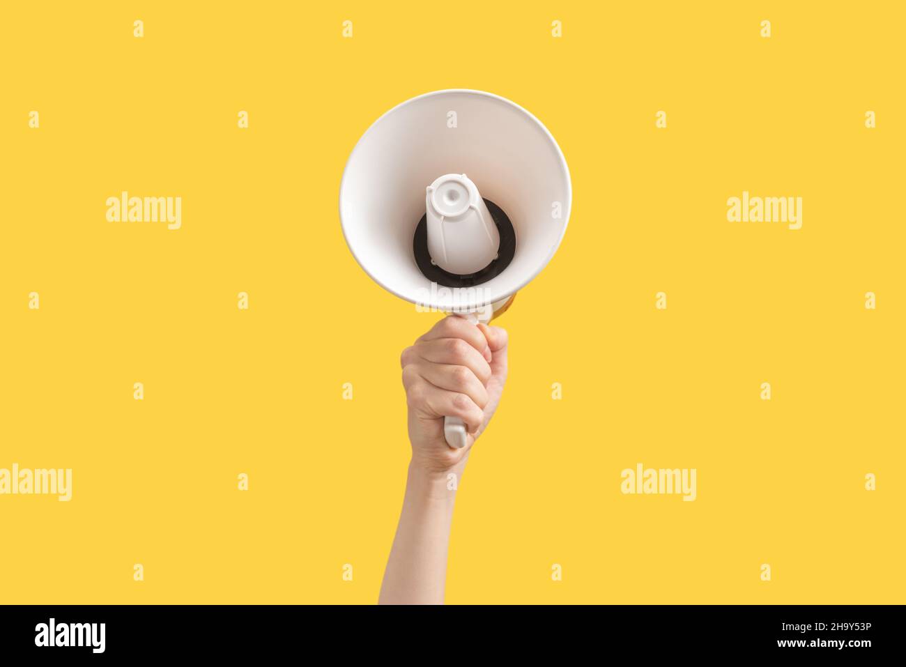 Megaphone in woman hands on a yellow background.  Copy space. Stock Photo