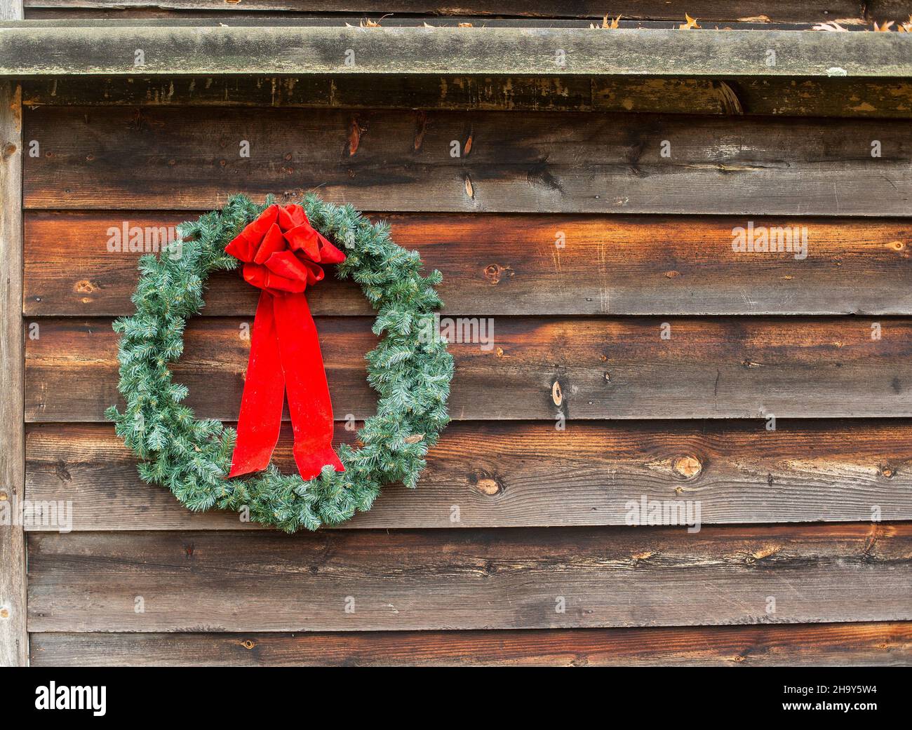 A Christmas wreath on a rustic barn wall Stock Photo
