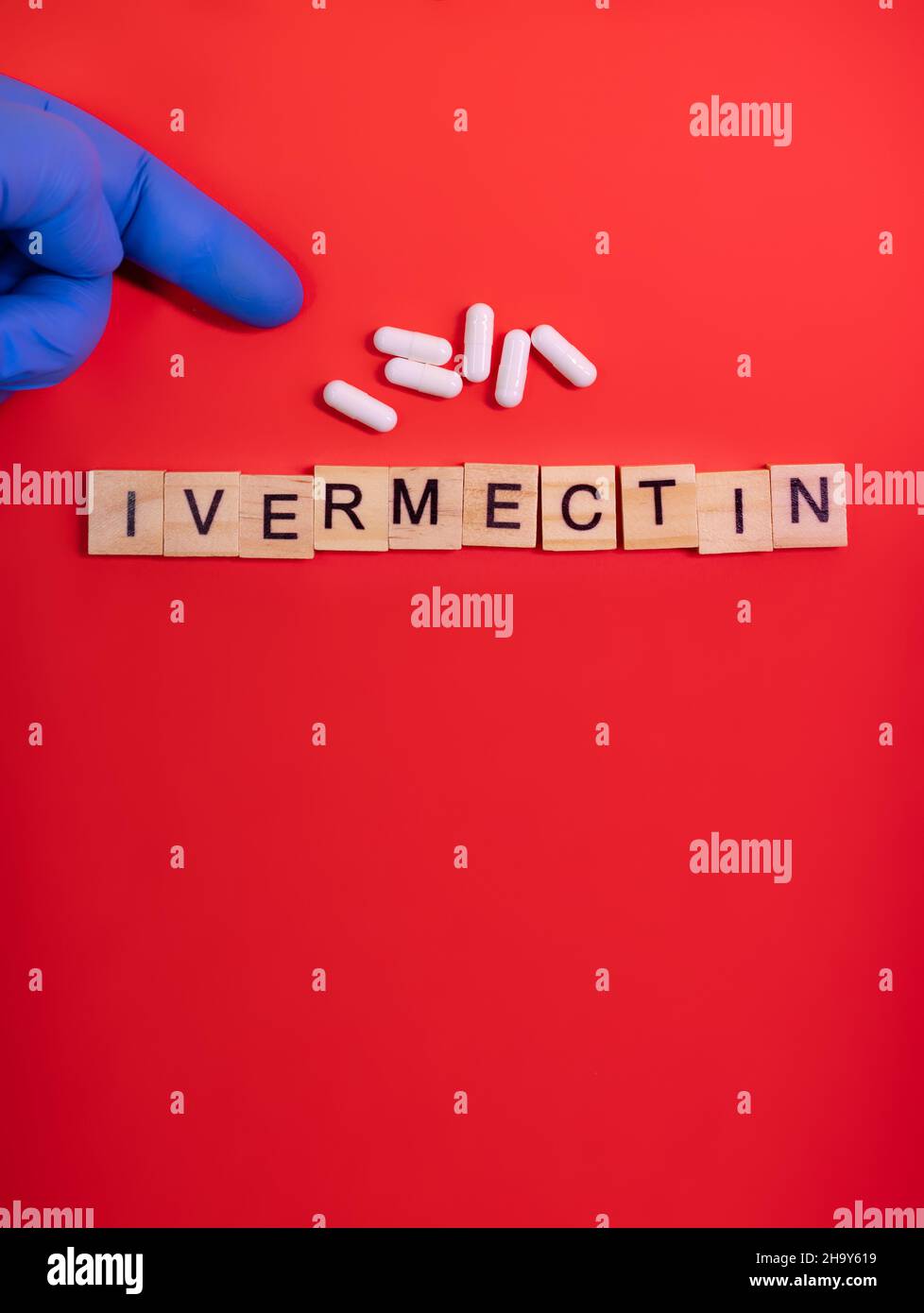 Ivermectin on colored red paper texture background. Ivermectin antiparasitic medication. Off label approved medicine drugs use. Covid-19 therapy. Phar Stock Photo