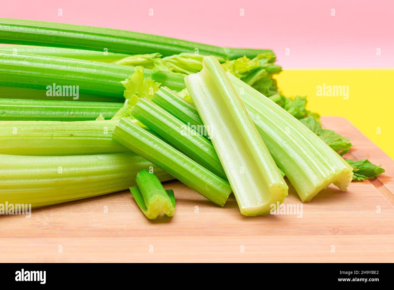 Fresh Celery Stem and Chopped Celery Sticks on Wooden Cutting Board. Vegan and Vegetarian Culture. Raw Food. Healthy Diet with Negative Calorie Content. Slimming Food Stock Photo