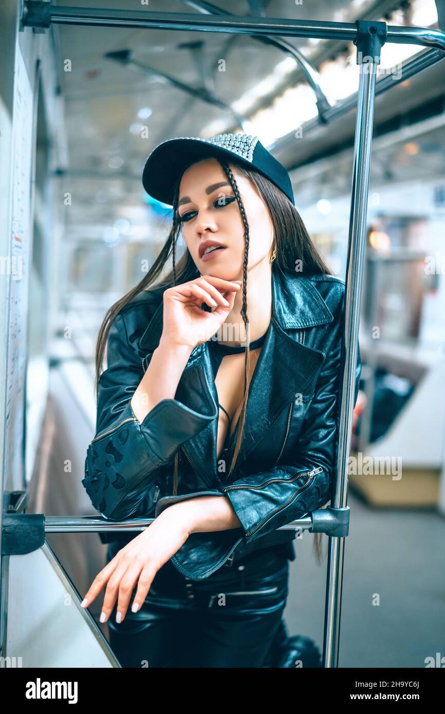 delightful Woman in stylish trendy clothes stands in a beautiful pose in a subway car. disco girl returns home at night from a party by subway. Close-up Portrait. High quality photo Stock Photo