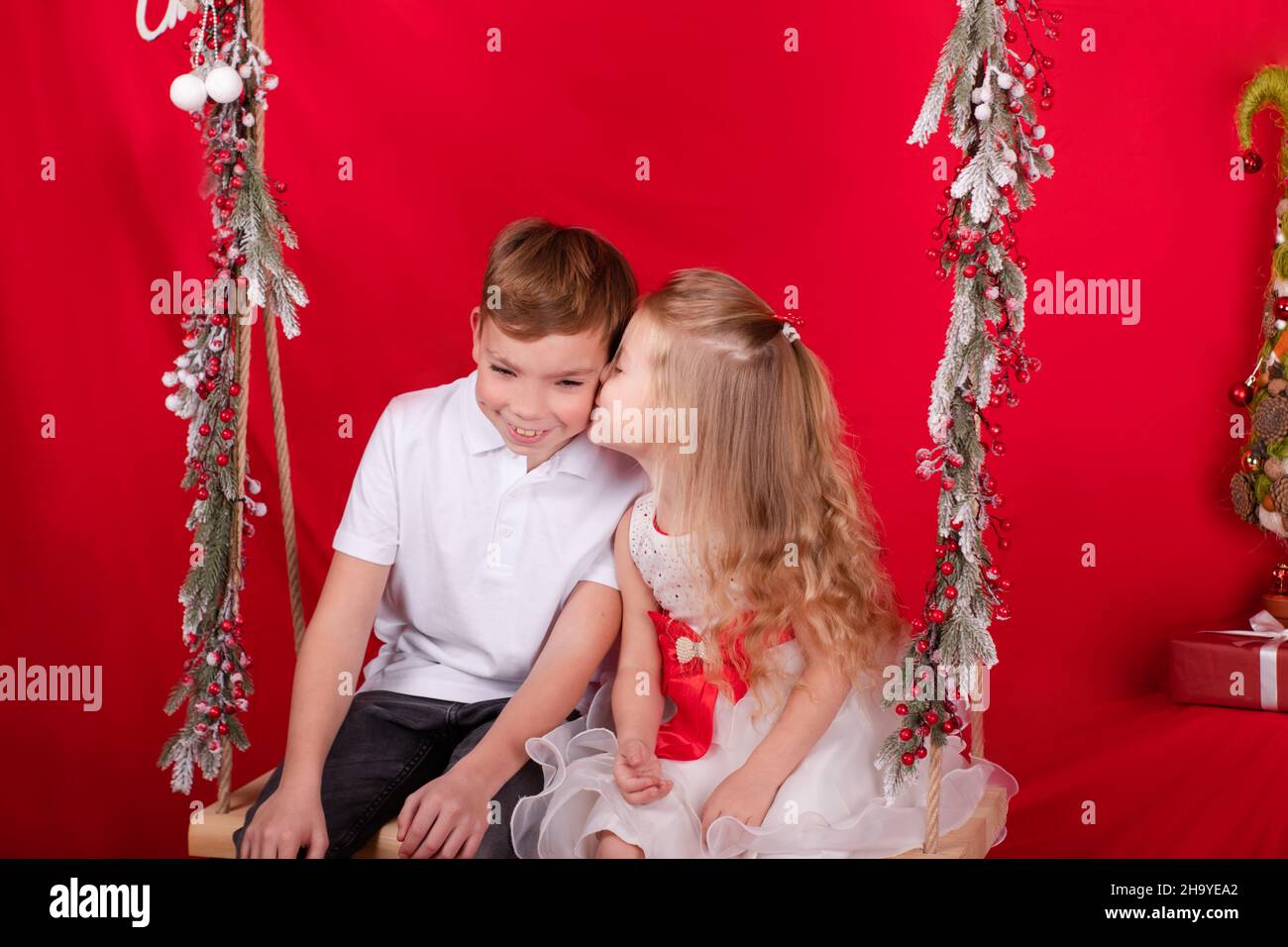 boy and girl - sister and brother - sitting on a swing decorated with ...
