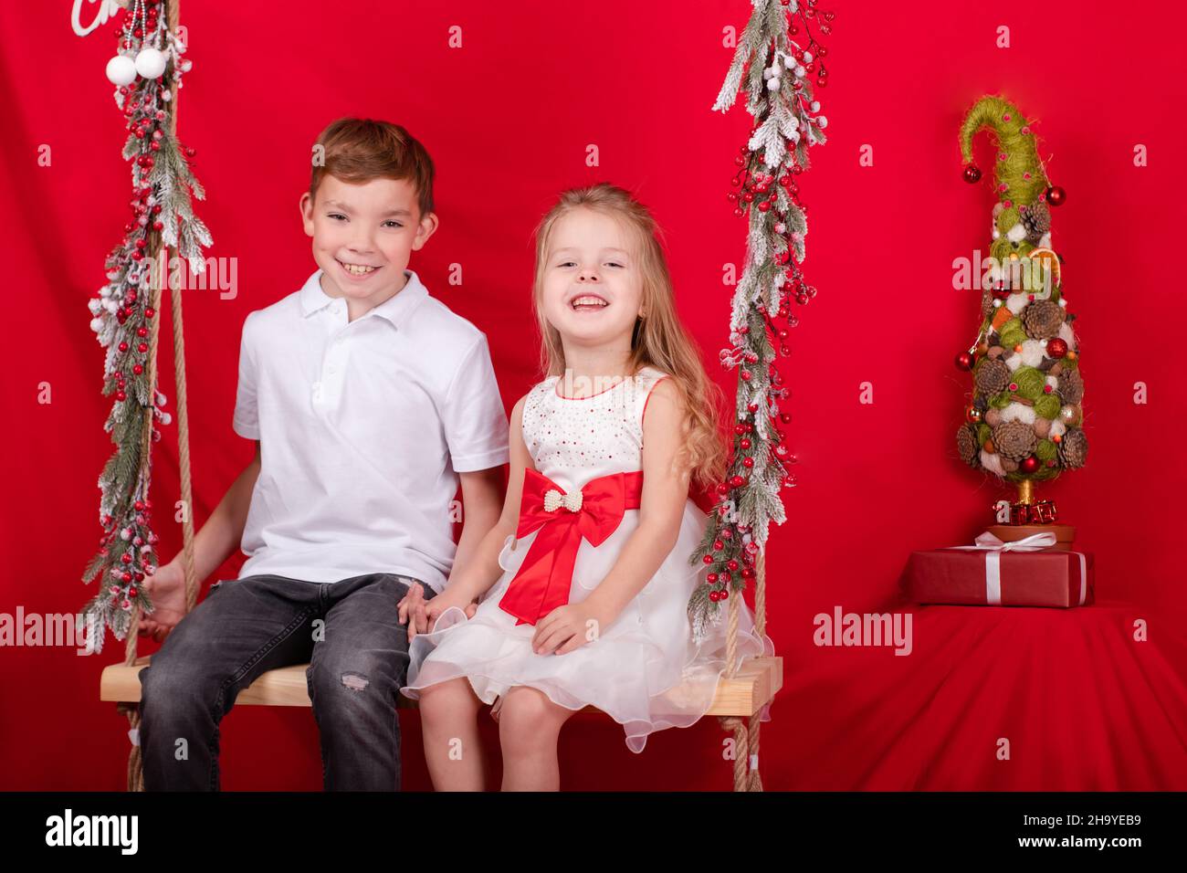 boy and girl - sister and brother - sitting on a swing decorated with ...
