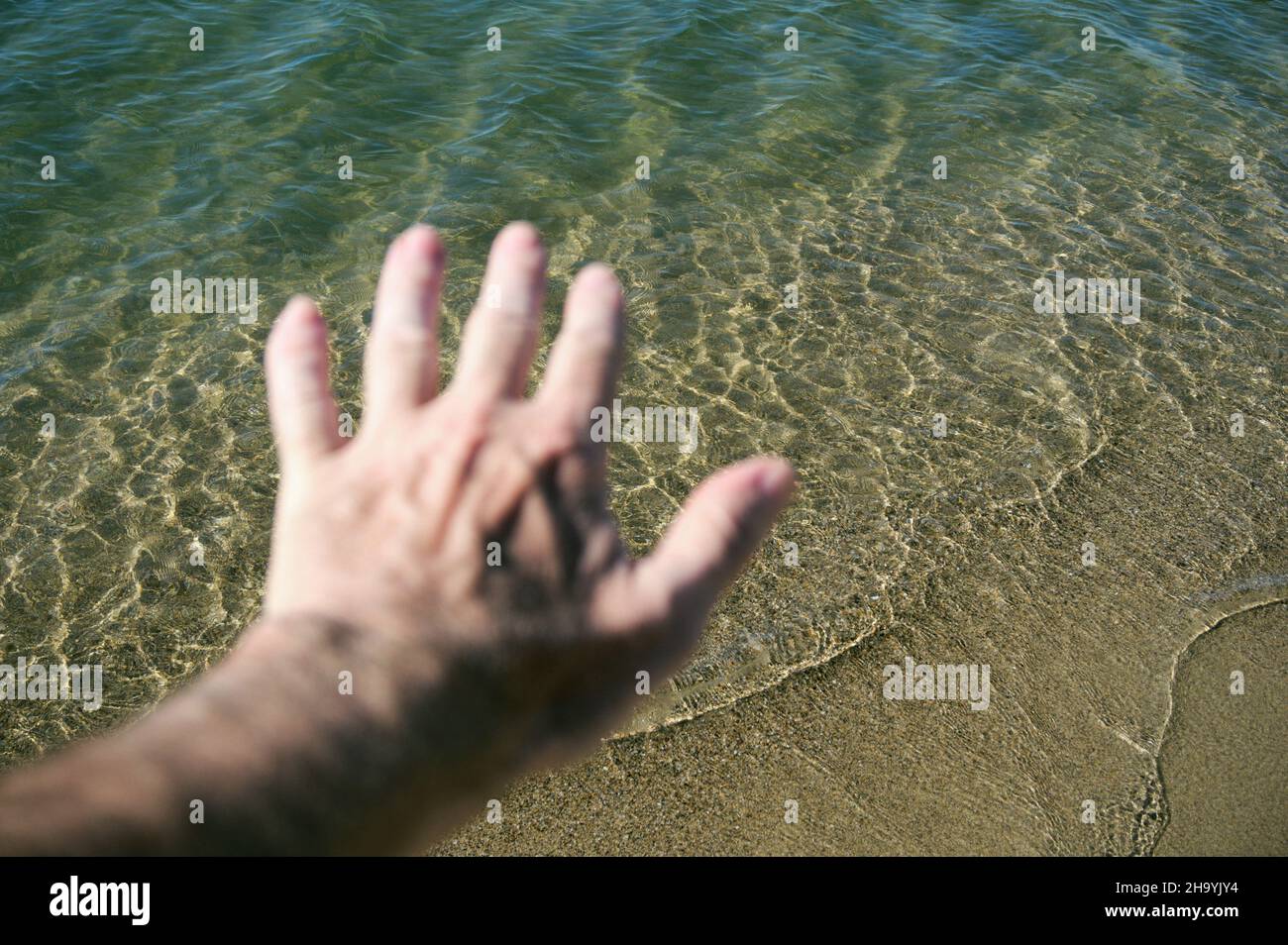 defocused male's arms stretch towards the sea Stock Photo