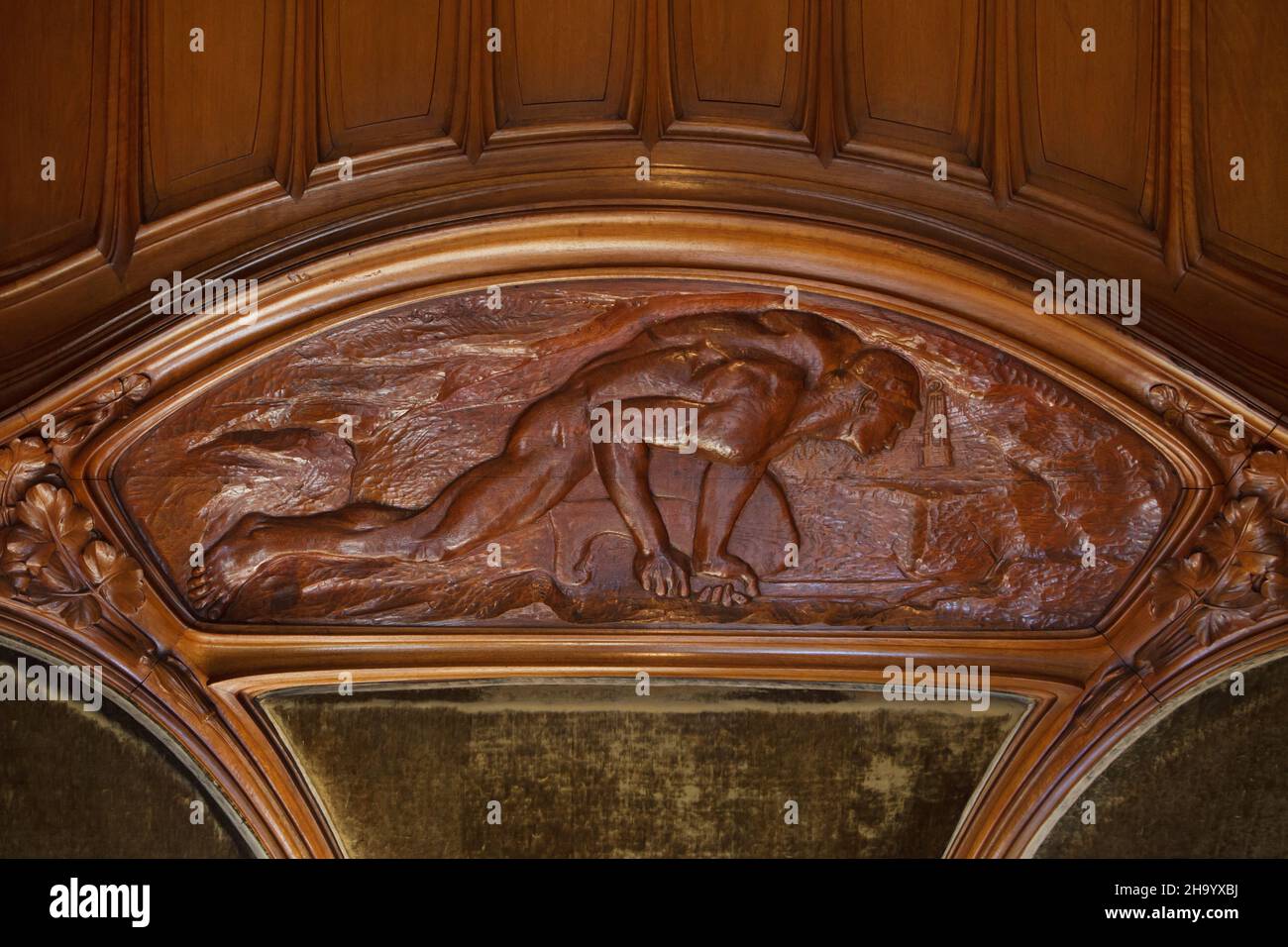 Naked miner depicted in the carved wooden panel on the Art Nouveau bench-library for minors designed by French furniture designer Eugène Vallin (1902) on display in the Museum of the Nancy School (Musée de l'École de Nancy) in Nancy, France. Stock Photo