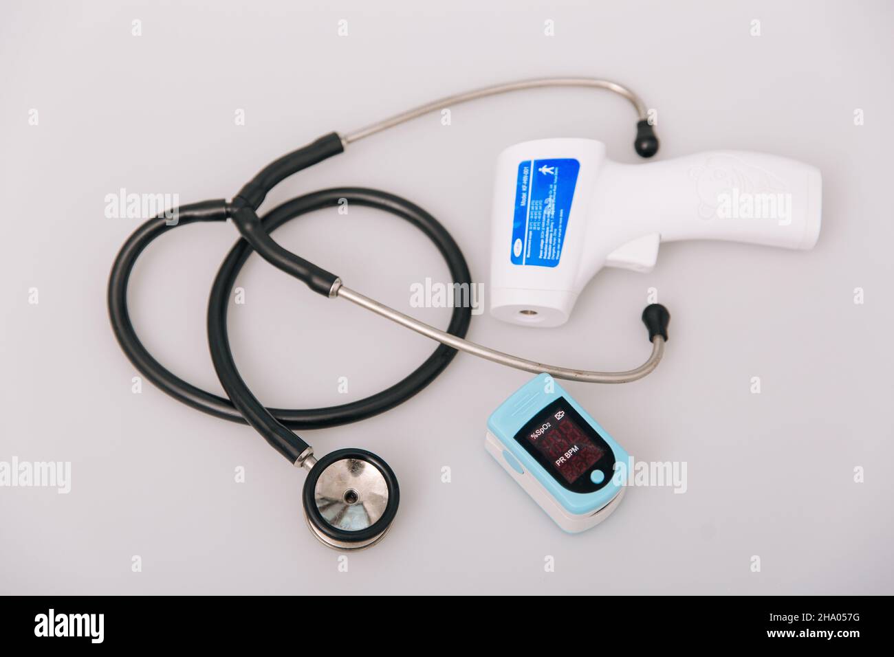 Stethoscope, pulse oximeter and thermometer gun on white background. Phonendoscope. Infrared isometric thermometer gun to check body temperature for Stock Photo