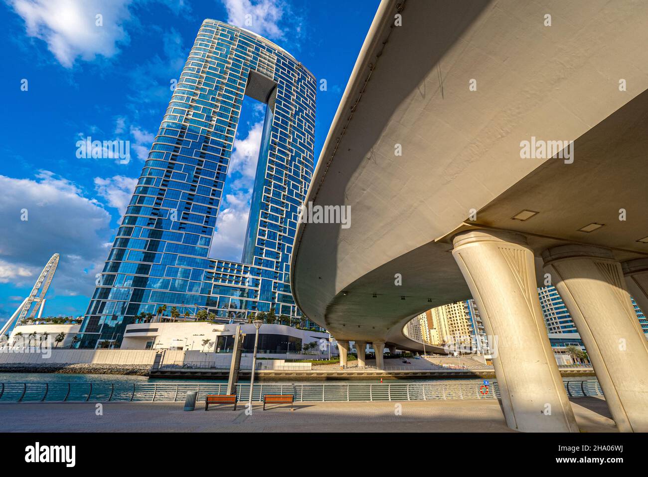 View of a modern hotel complex building raising at the end of the Dubai Marina district next to the waterway inlet and a highway bridge, Dubai, UAE Stock Photo