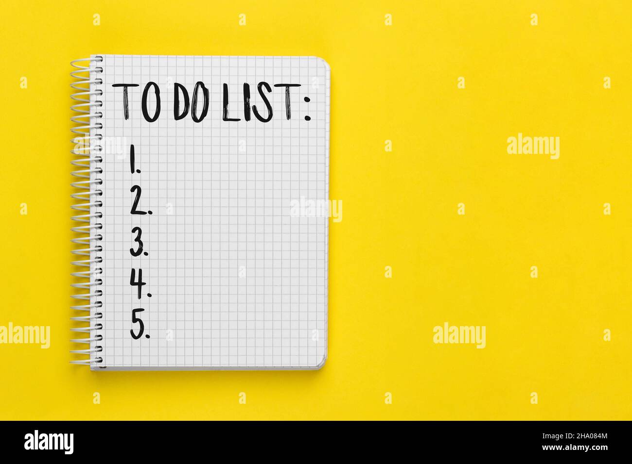 Open spiral squared notebook with to do list on bright yellow background with copy space, top view, flat lay Stock Photo