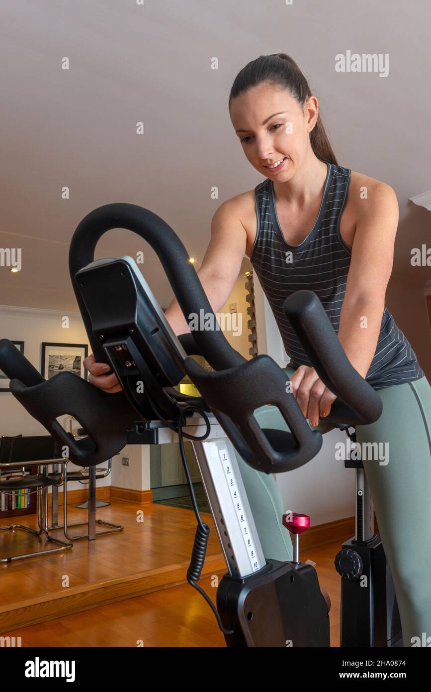 Woman Exercising on Spin Bike in Home Stock Photo