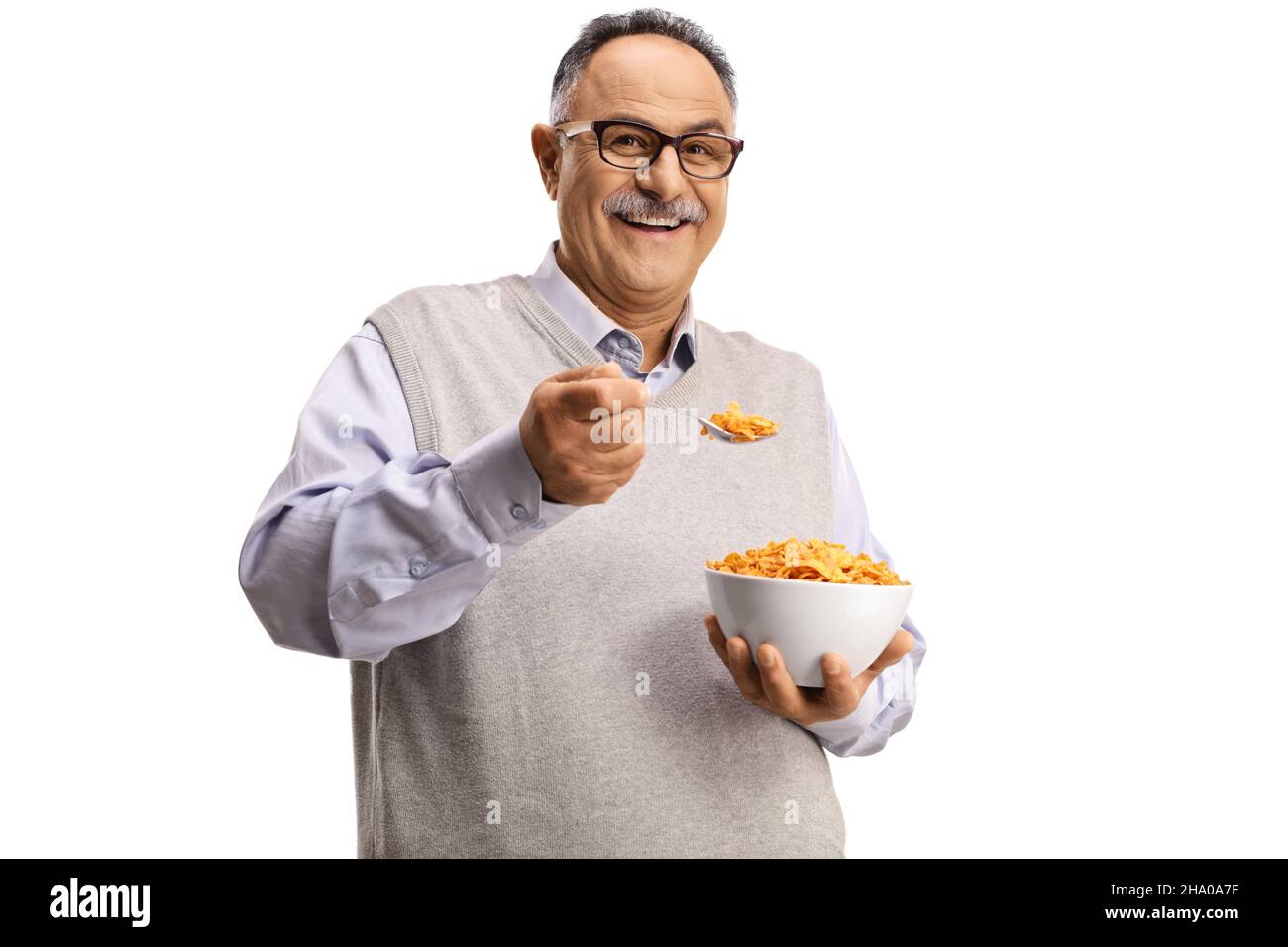 Smiling mature man standing and eating cornflakes isolated on white