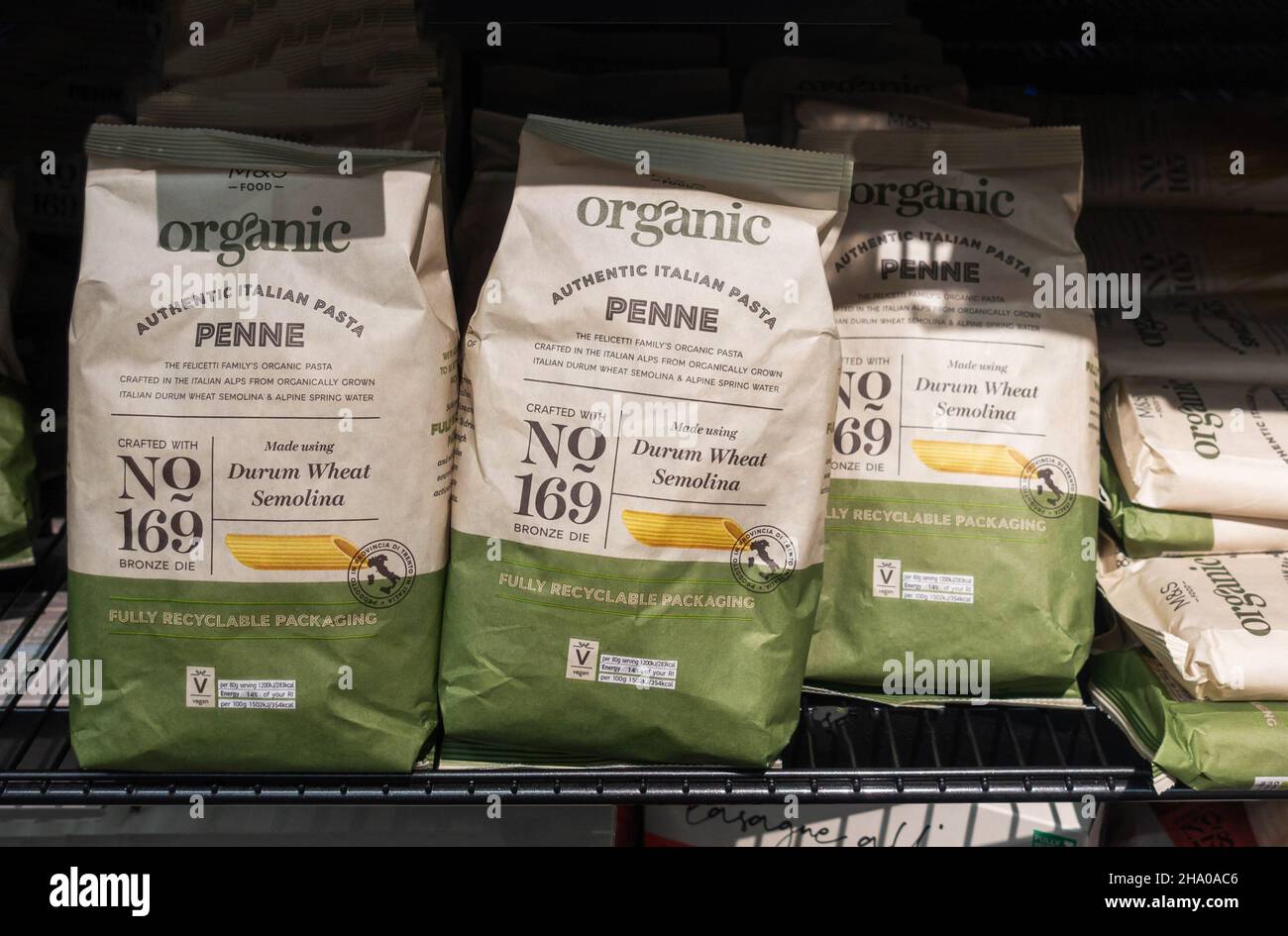 Bags of organic penne pasta on a. shelf in M&S foodhall Stock Photo