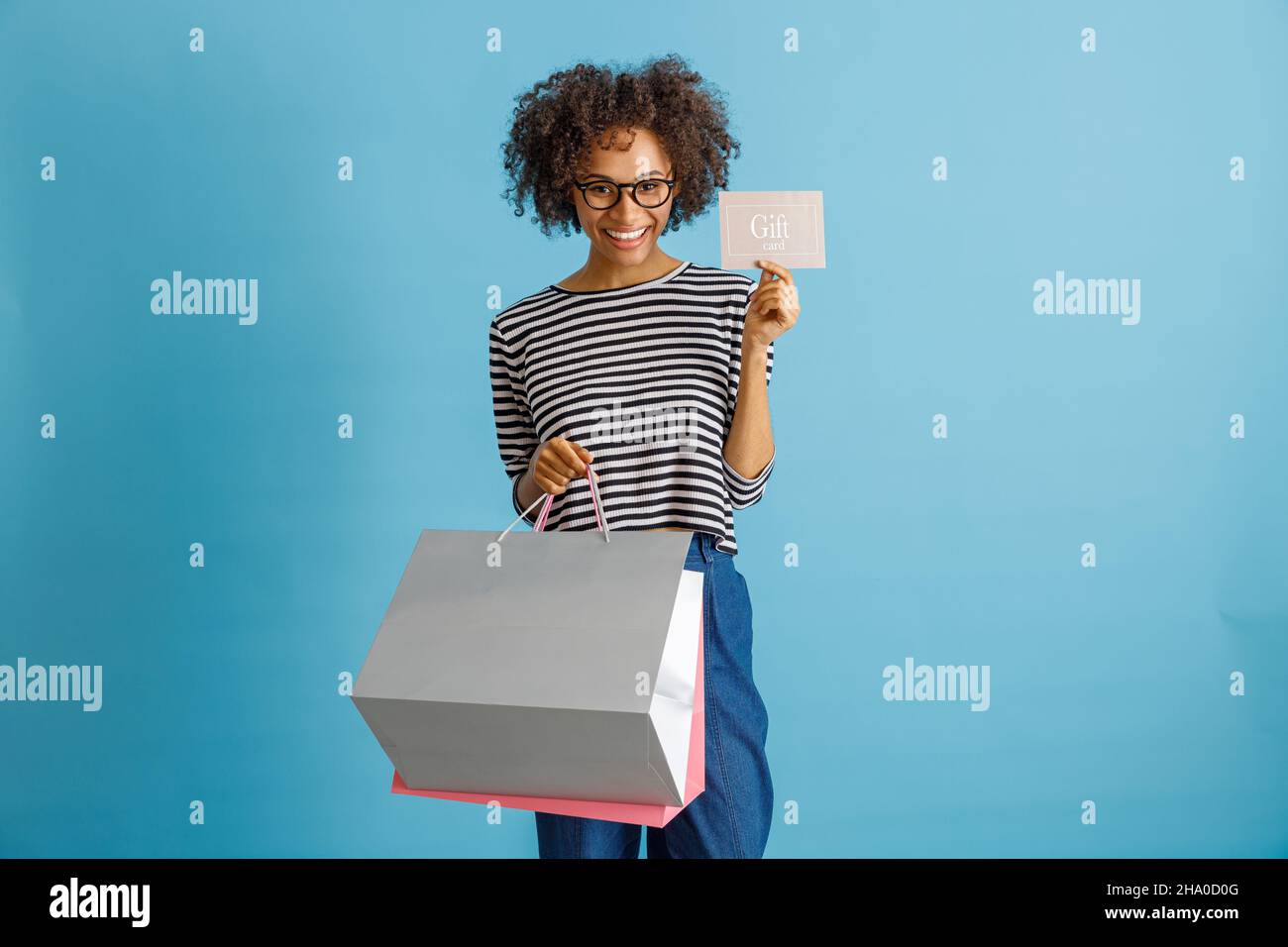 Joyful young woman holding purchases and gift card Stock Photo - Alamy