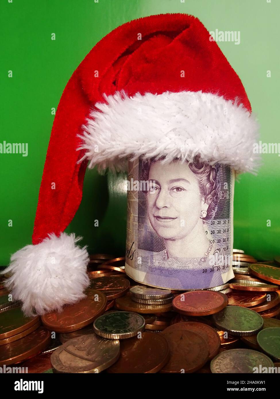 Bundle of British pounds in santa hat on top of British coins. Christmas savings concept Stock Photo