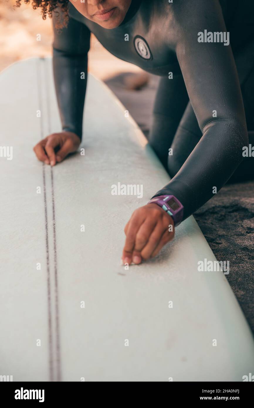 Female surfer waxing her surfboard on the beach Stock Photo Alamy