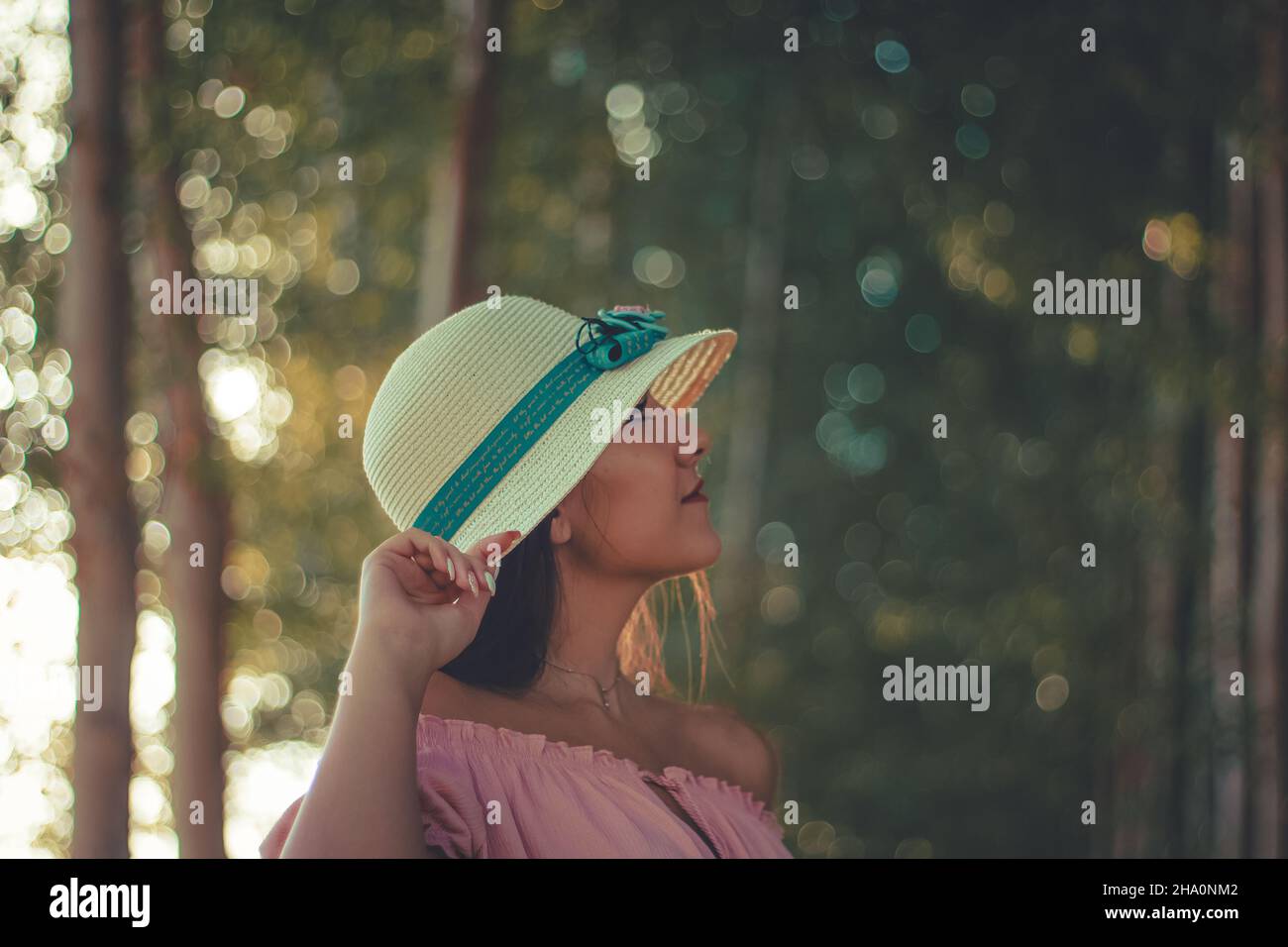 Close up portrait of a young hispanic girl wearing a white sun hat and pink blouse Stock Photo