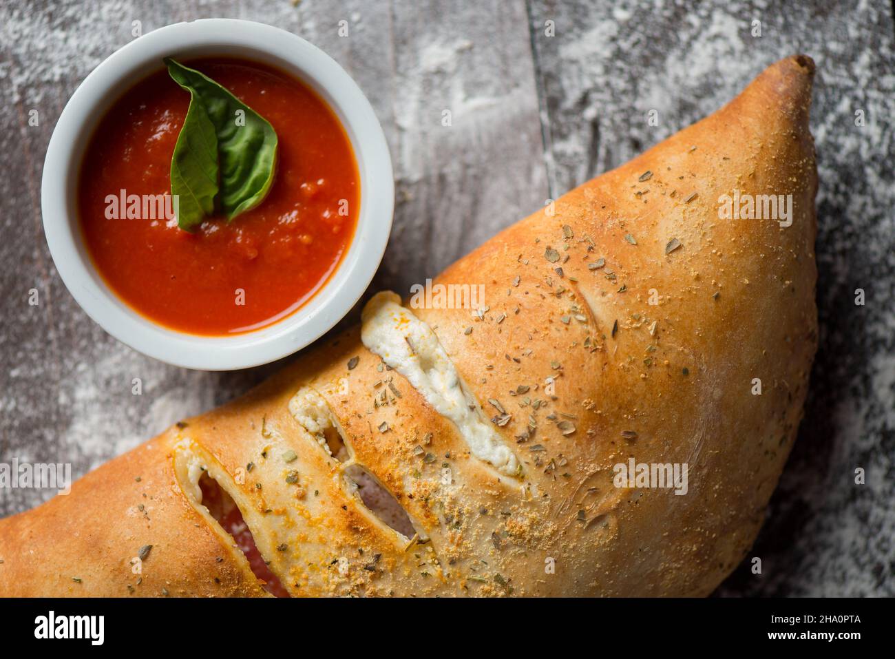 Calzone with marinara sauce over a wood with flour Stock Photo Alamy