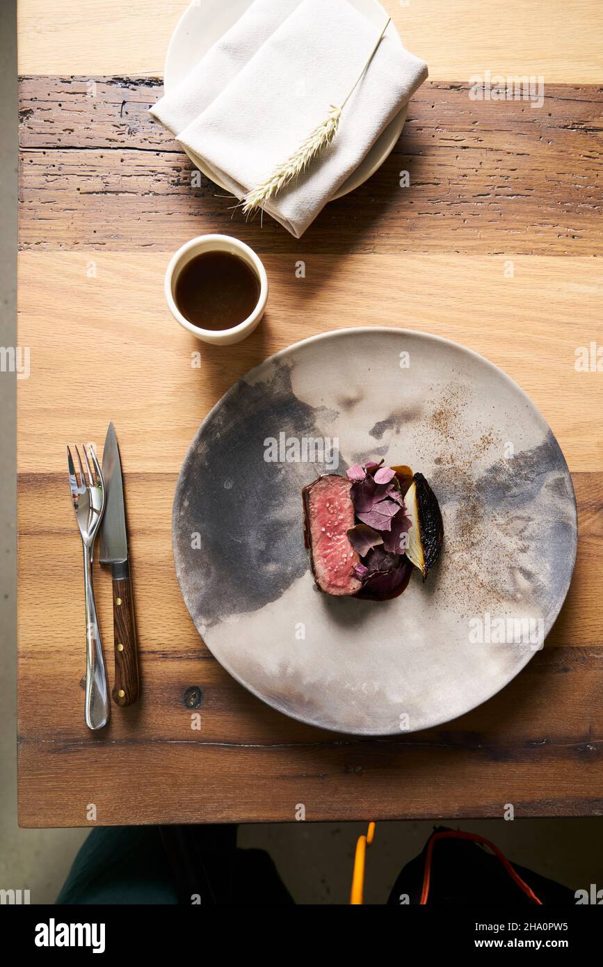Delicious steak dish with modern plating on ceramic plate & wood table Stock Photo