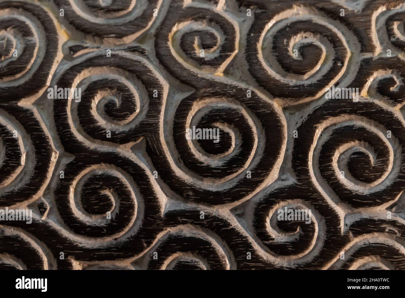 Dark wooden panel with carved spiral ornament, close up photo Stock Photo