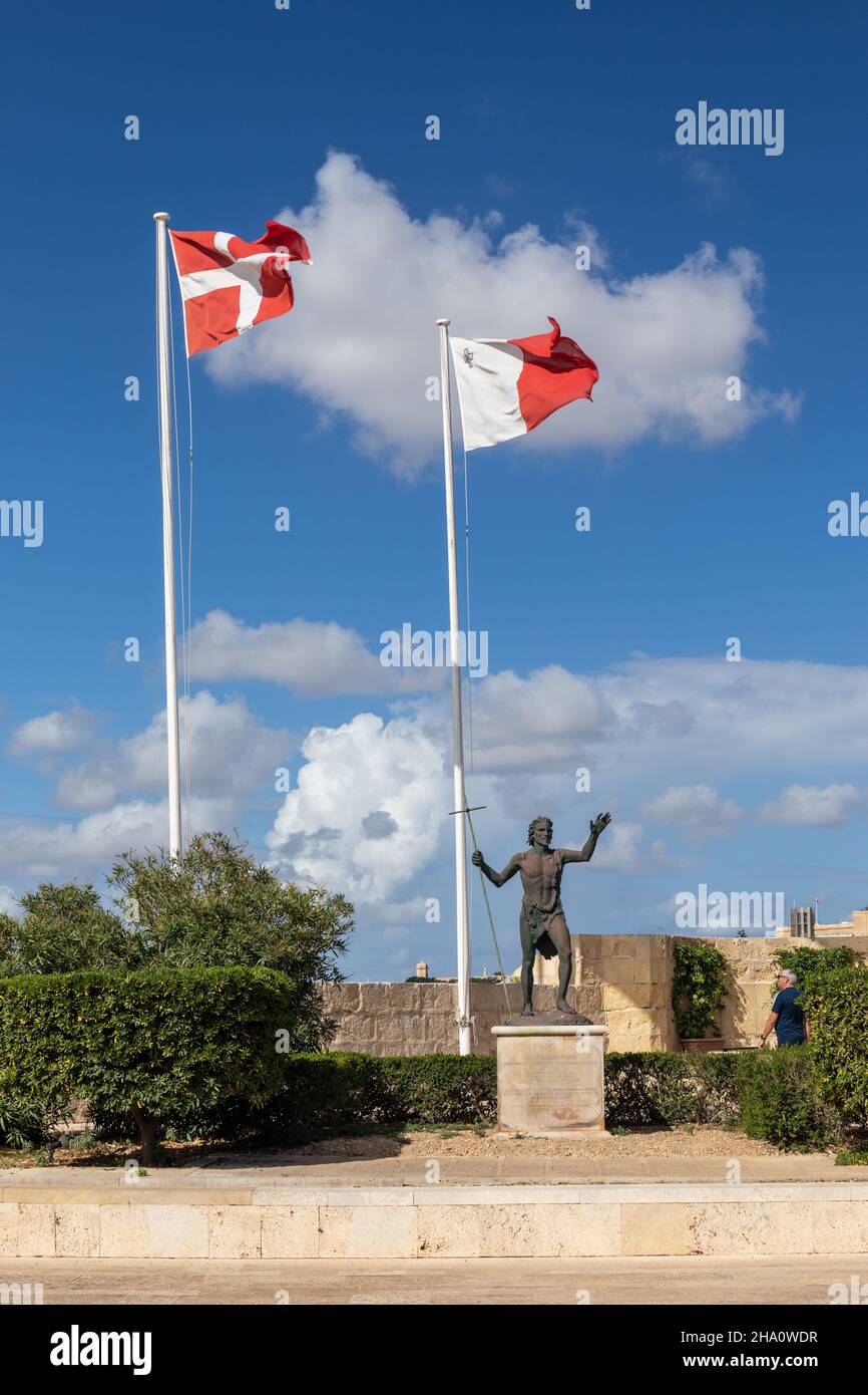 Statue of St John the Baptist & the flags of the Order of Knights of Malta & the Maltese flag. Fort St Angelo UNESCO World Heritage Site. Malta. Stock Photo