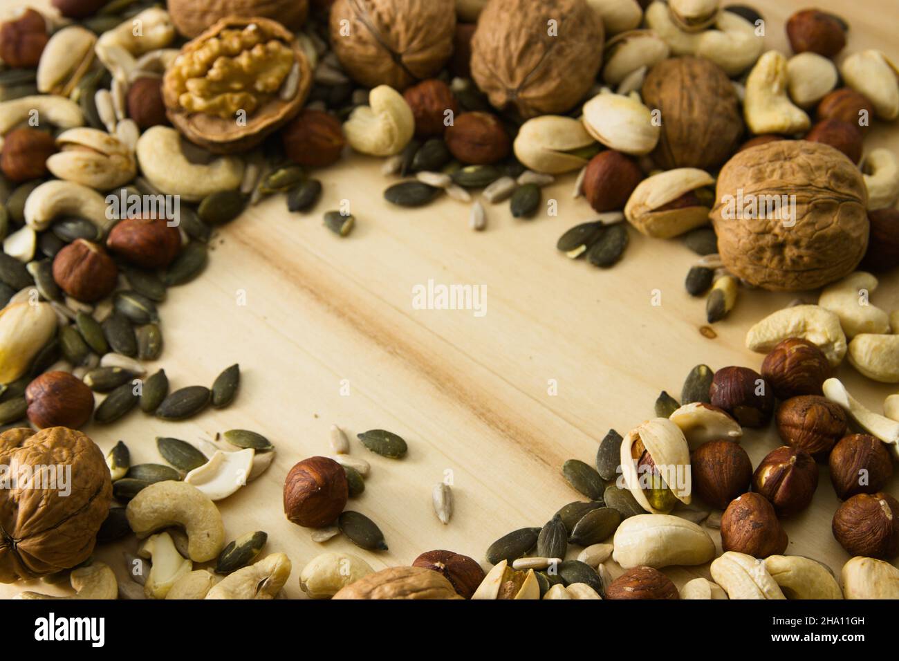 Image with copy space surrounded by different nuts among which walnuts, cashews, pumpkin seeds, pistachios and sunflower seeds stand out Stock Photo