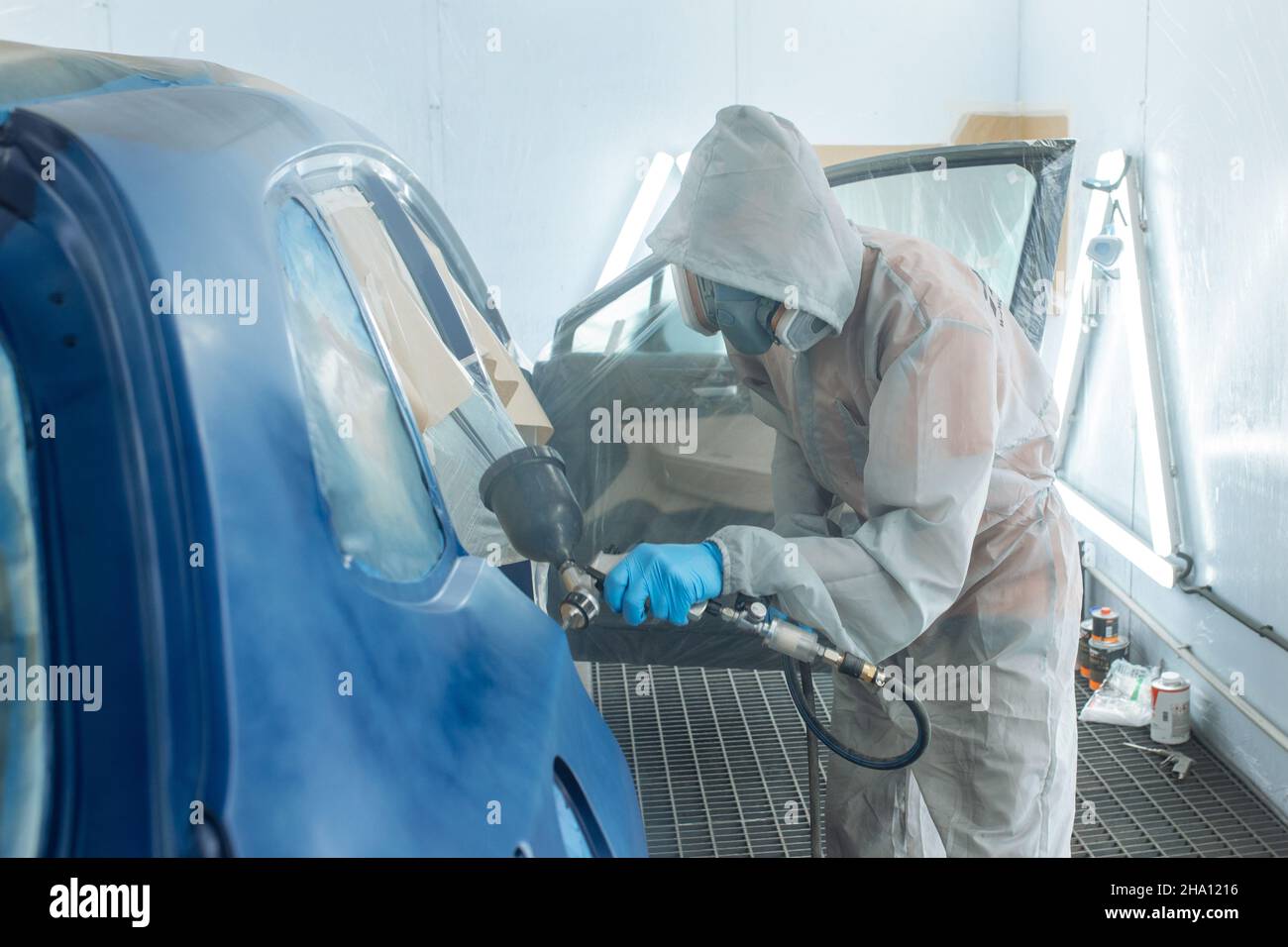 Professional car painter is painting in garage by airbrush Stock Photo