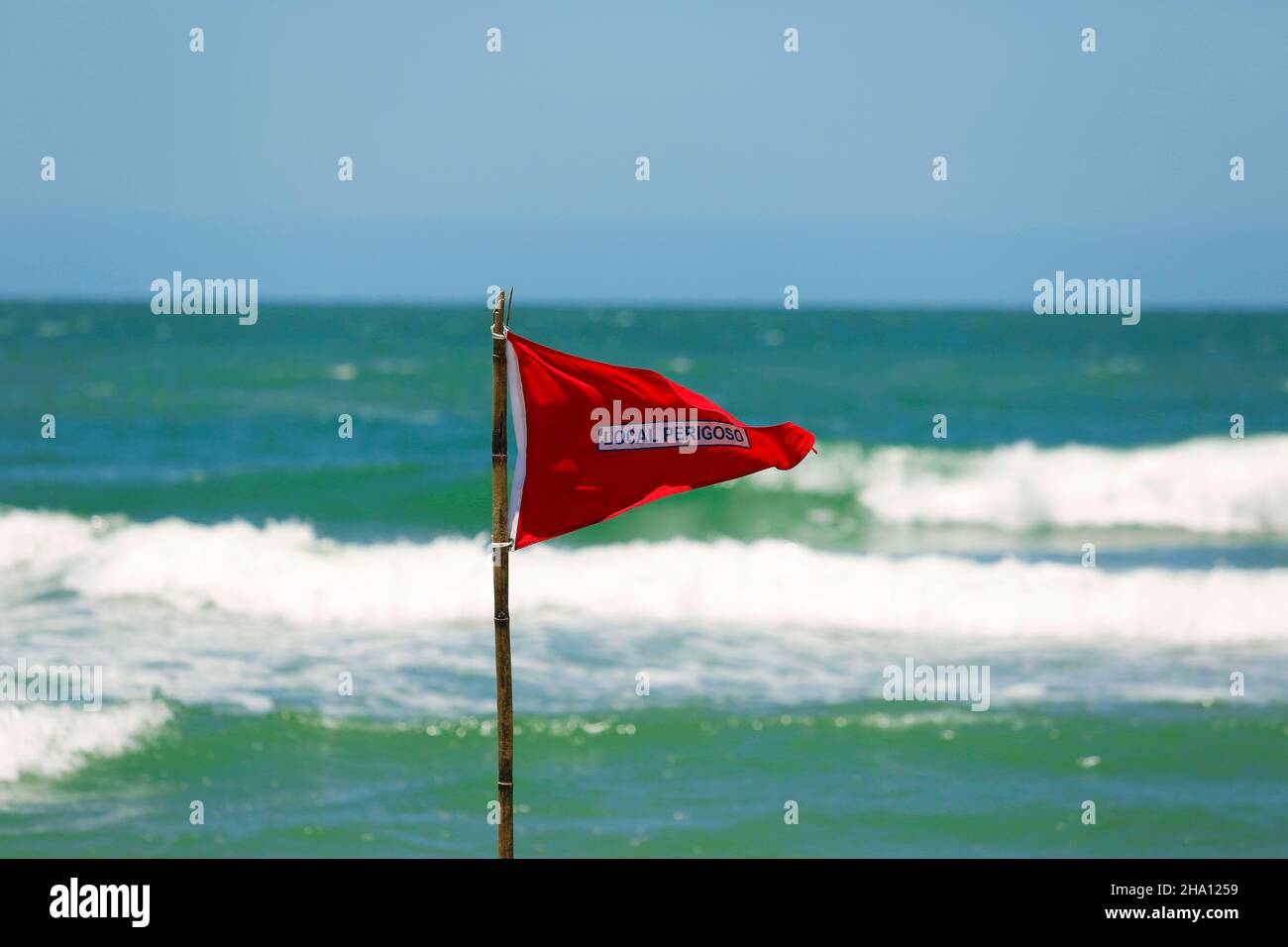 Red flag life guard danger warning sign on the beach. No swimming it's forbidden symbol, dangerous rip tide currents on water, enter at your on risk. Stock Photo