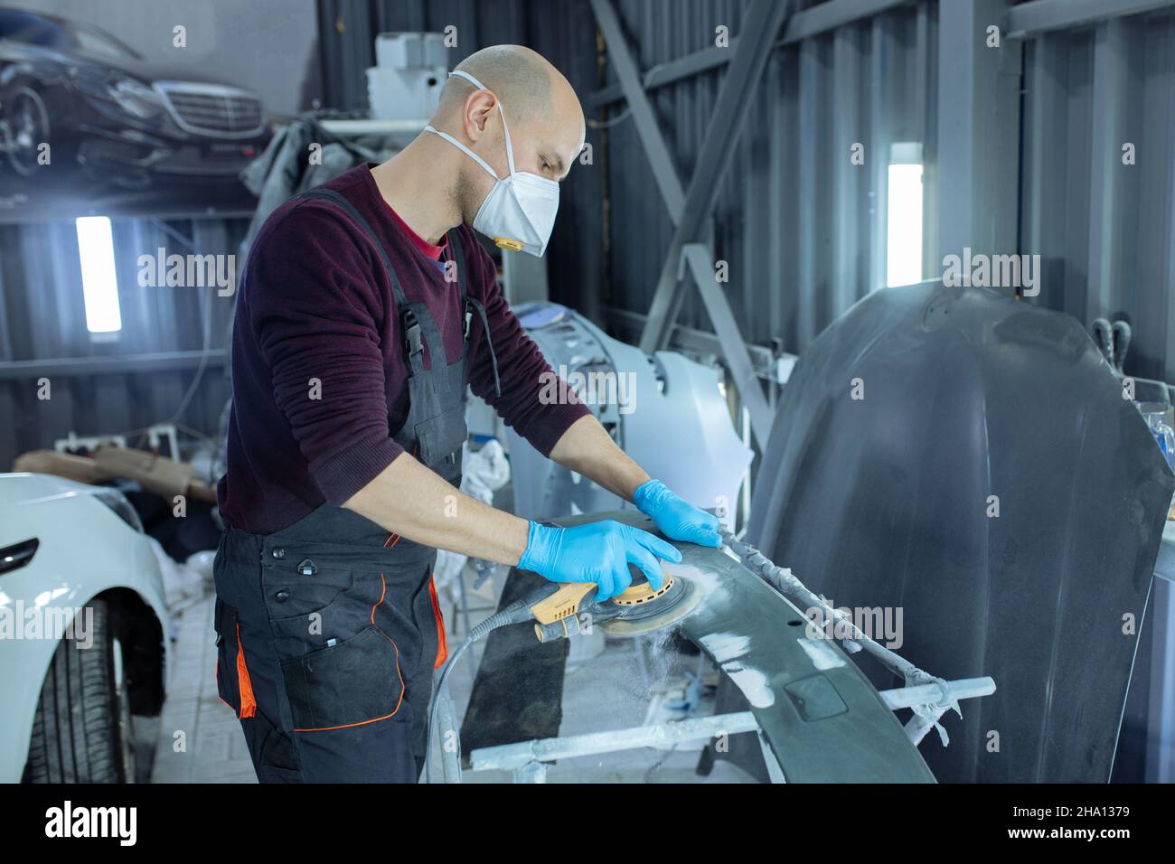 Sanding a car body part with electrical grinder machine before painting
