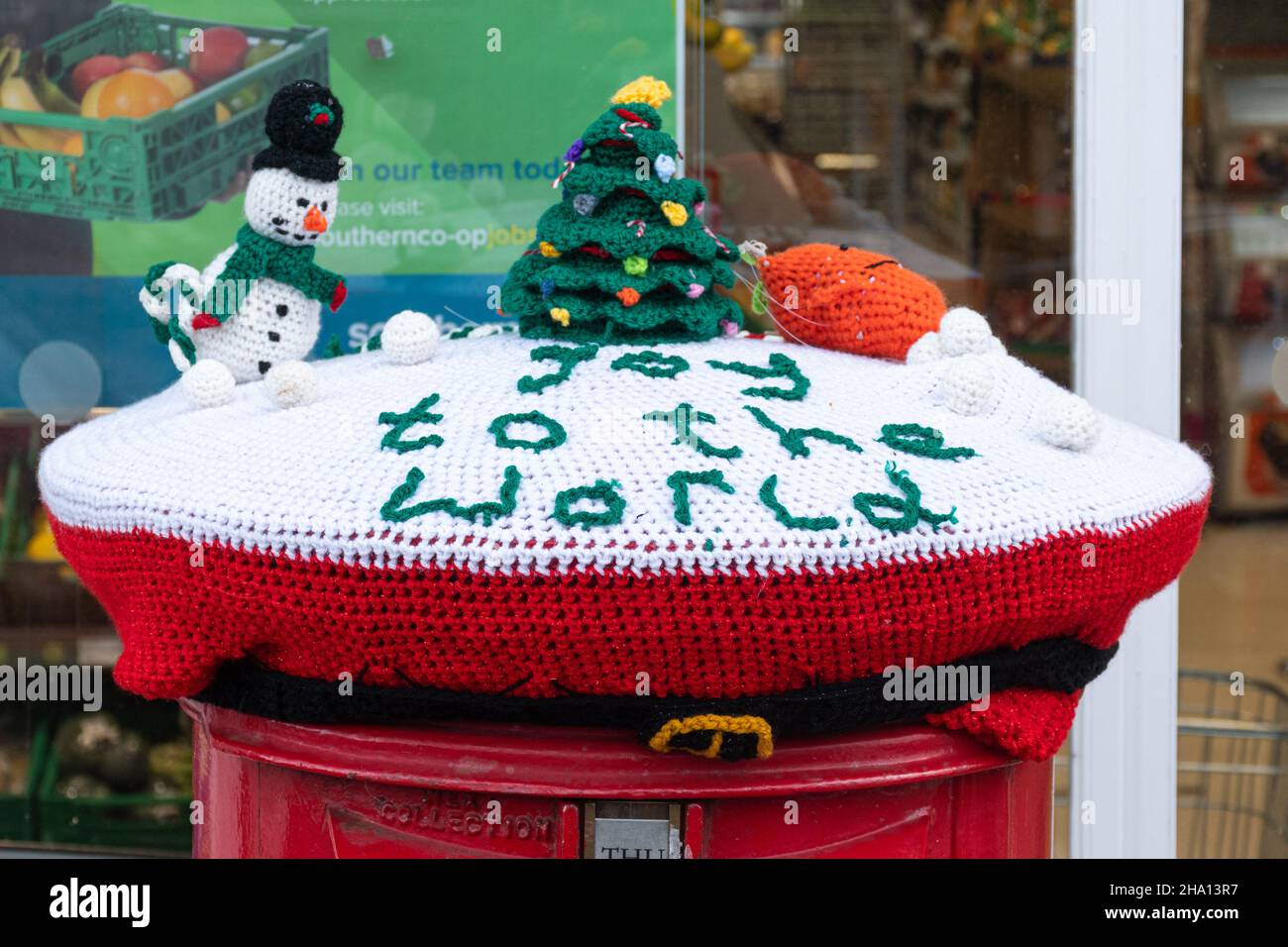 Yarn bombing, Christmas snow scene with knitted snowman and Christmas tree on top of a post box, UK Stock Photo