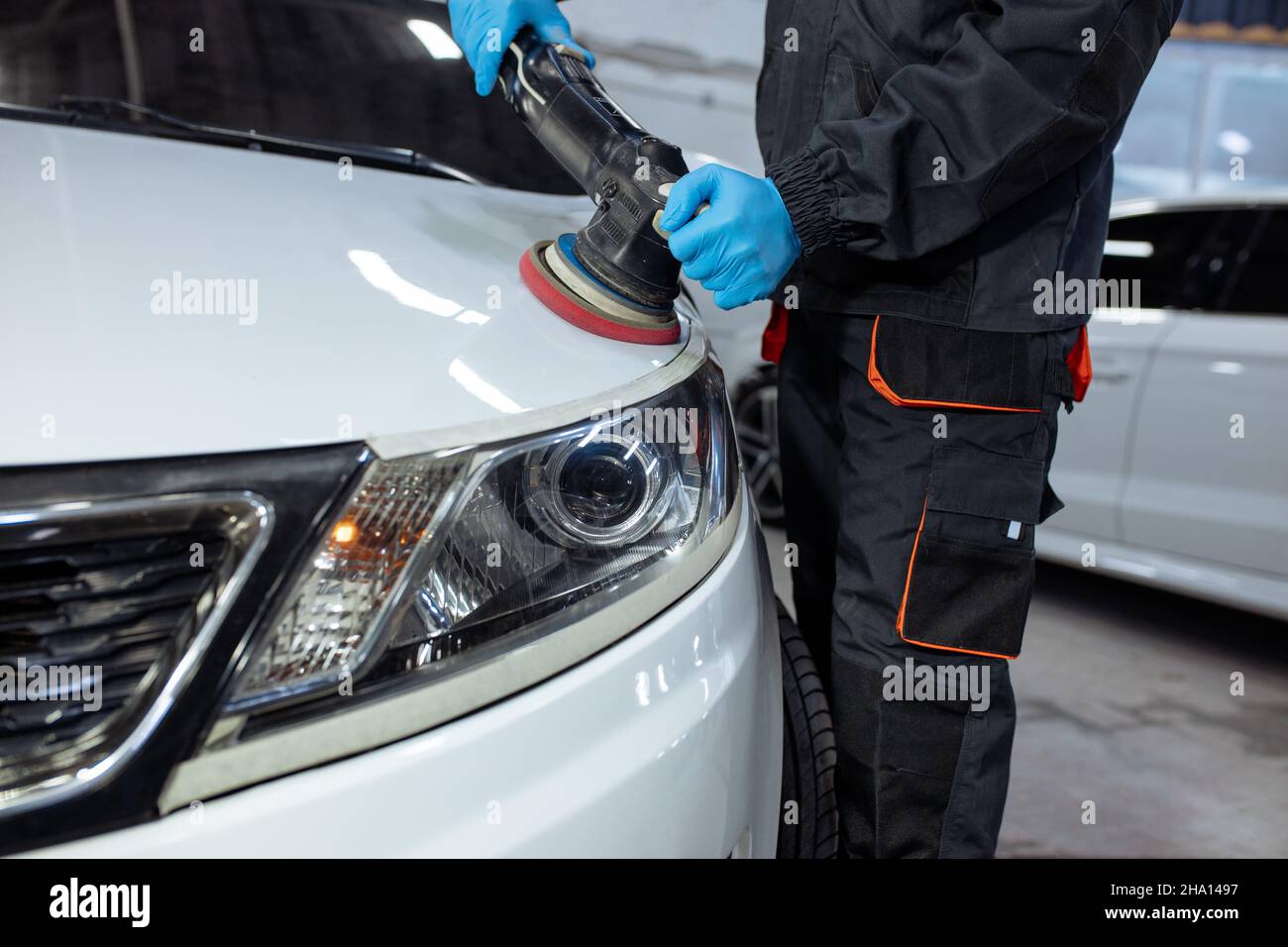 Serviceman polishing car body with machine in a workshop. Stock Photo