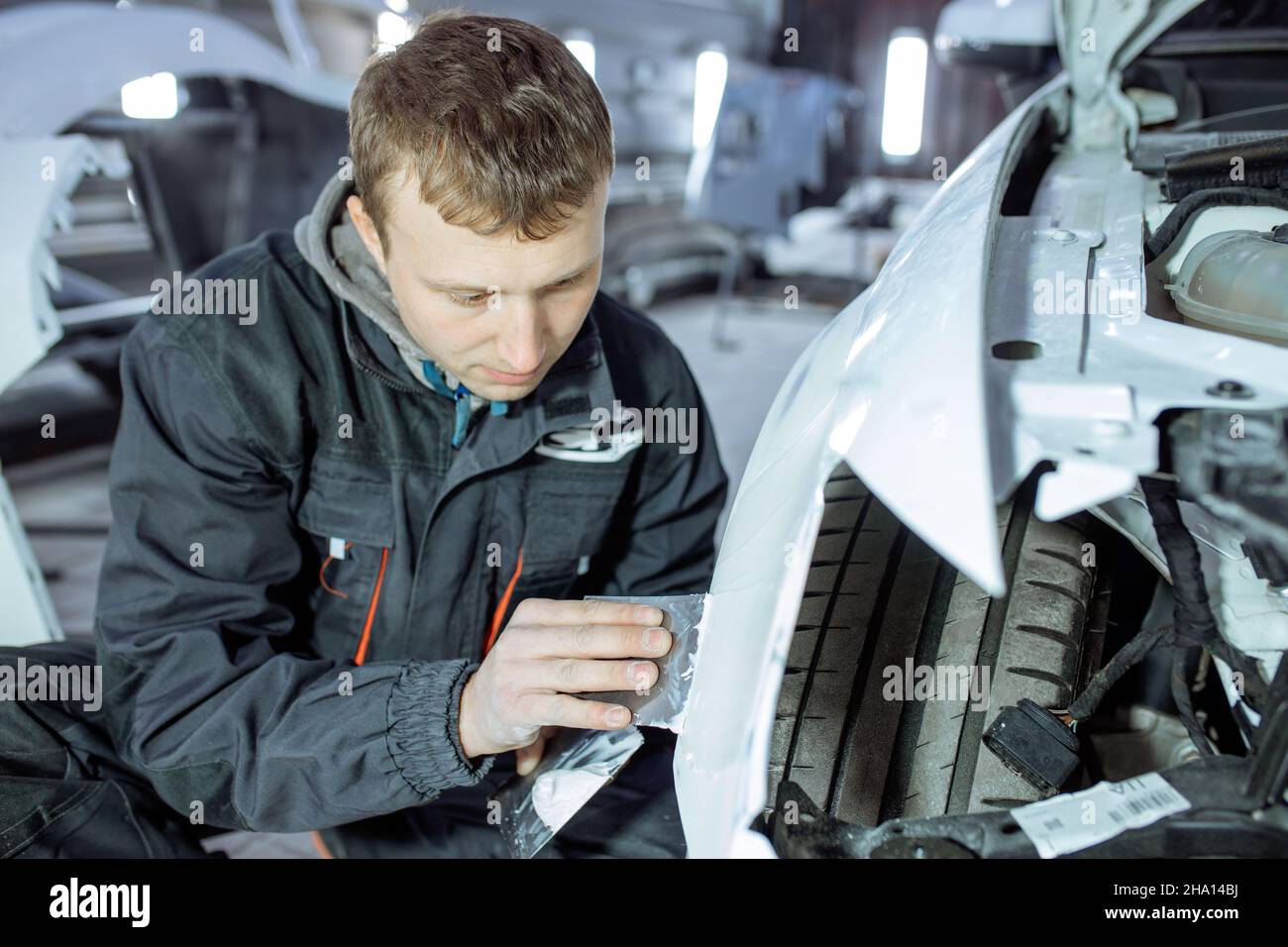 Repairing car body by puttying close up work after the accident by