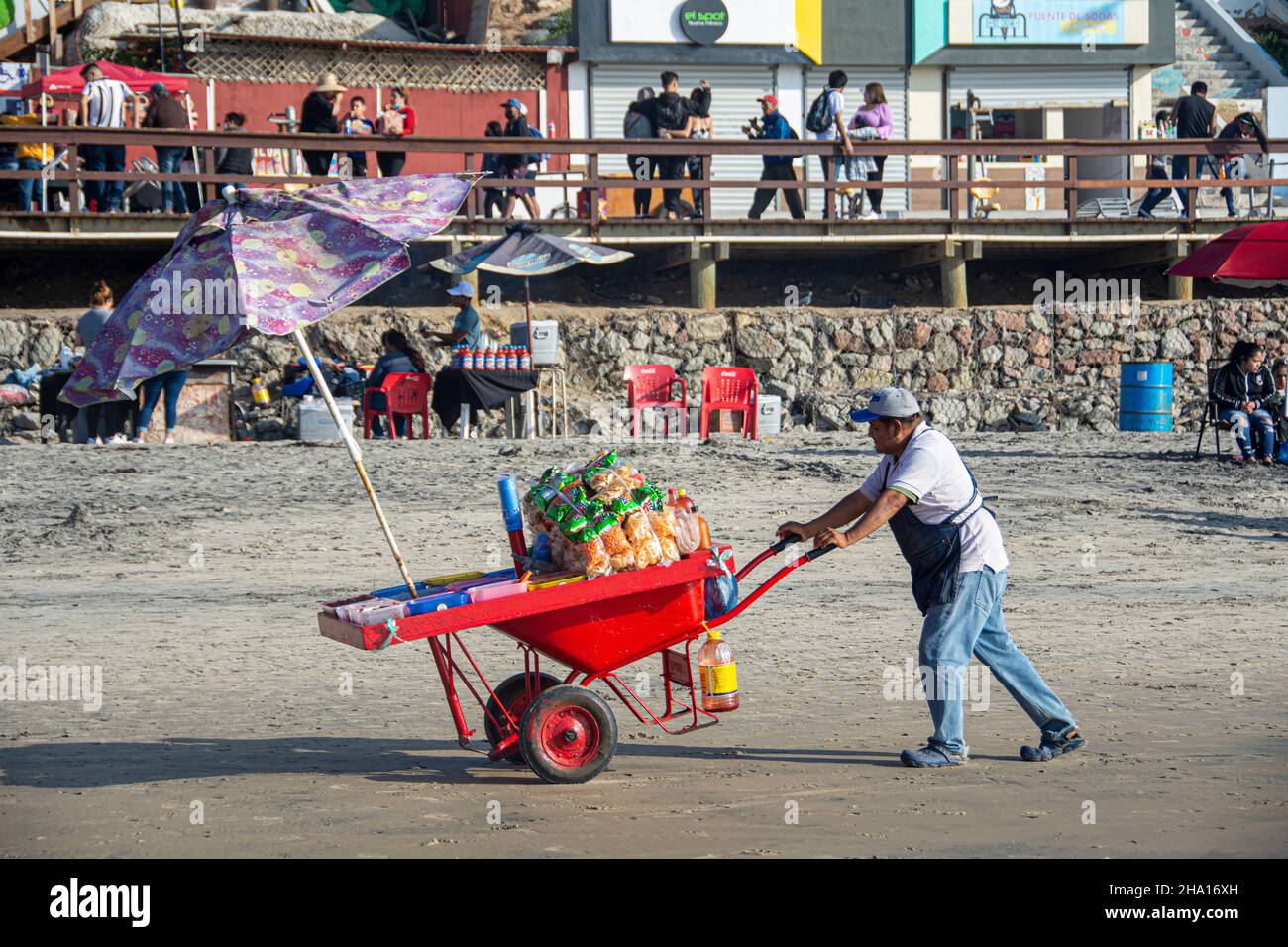 A Mexican vender pushes his cart laden with vegetables across the sand of Tijuana Beach, (Playas de Tijuana) Baja California, Mexico. Stock Photo