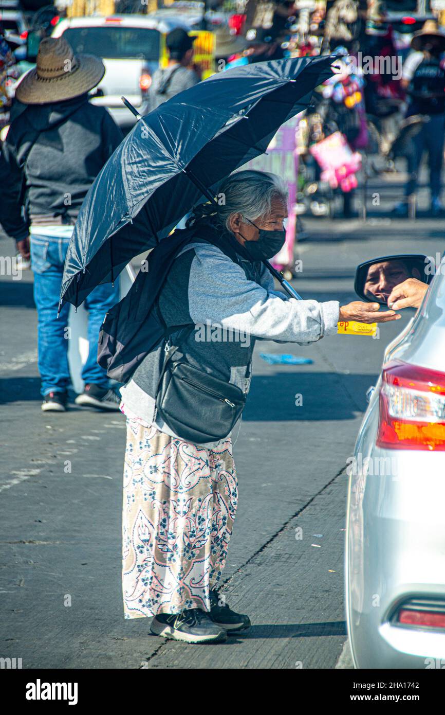A woman vender in her 80s sells some gum to a driver crossing the San Ysidro, USA/Tijuana, Mexico border point in Southern, California. Stock Photo